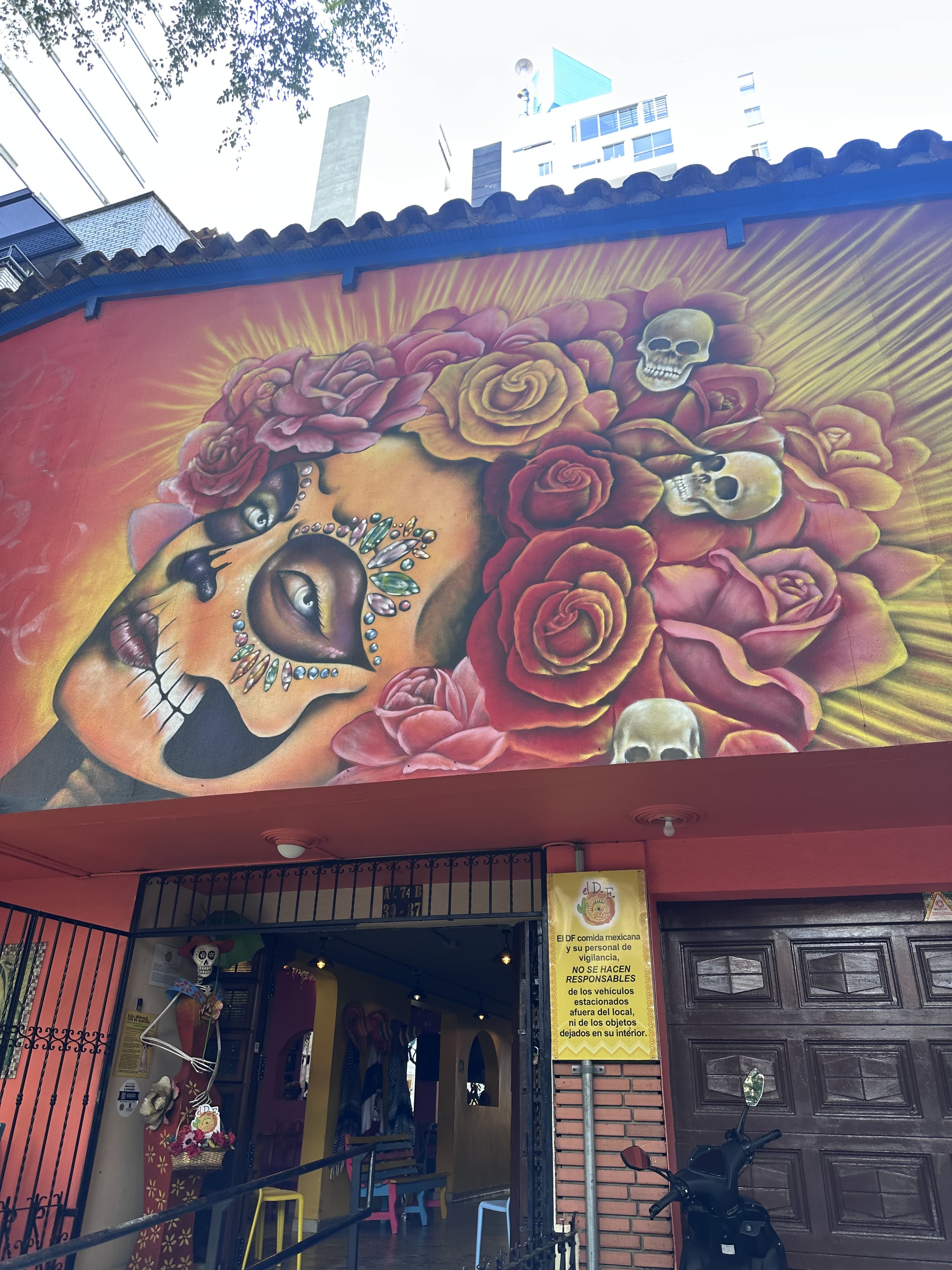 Colorful mural of a woman's face with floral and skull details above the entrance of a Mexican restaurant in Medellín Colombia.