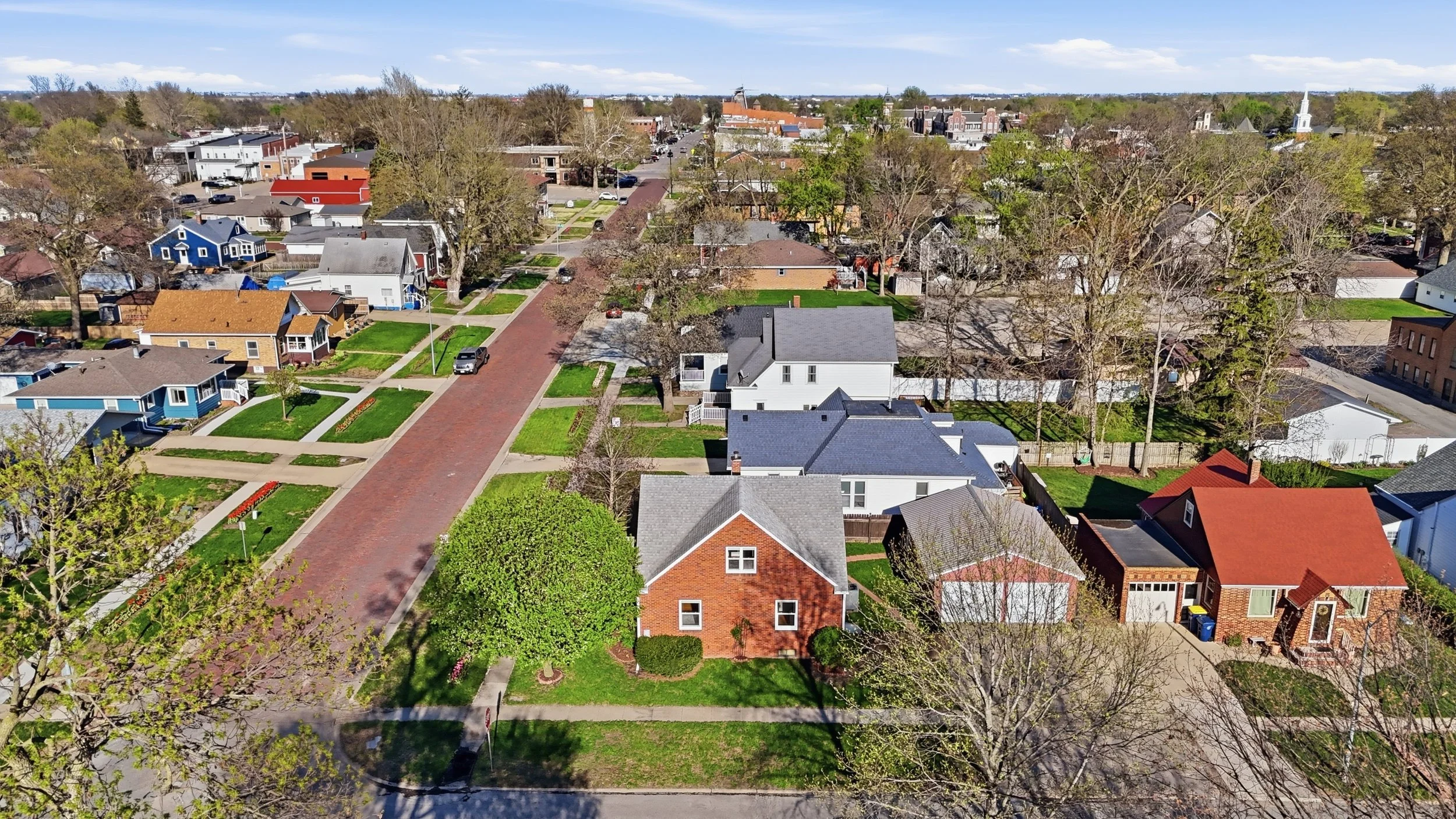 Aerial view of a residential neighborhood with houses, trees, and streets on a sunny day.