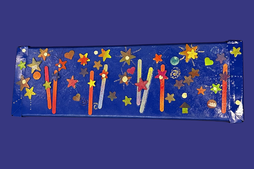 A blue box decorated with colorful star-shaped and heart-shaped stickers, and glitter, resembling a celebratory or festive gift or decoration.