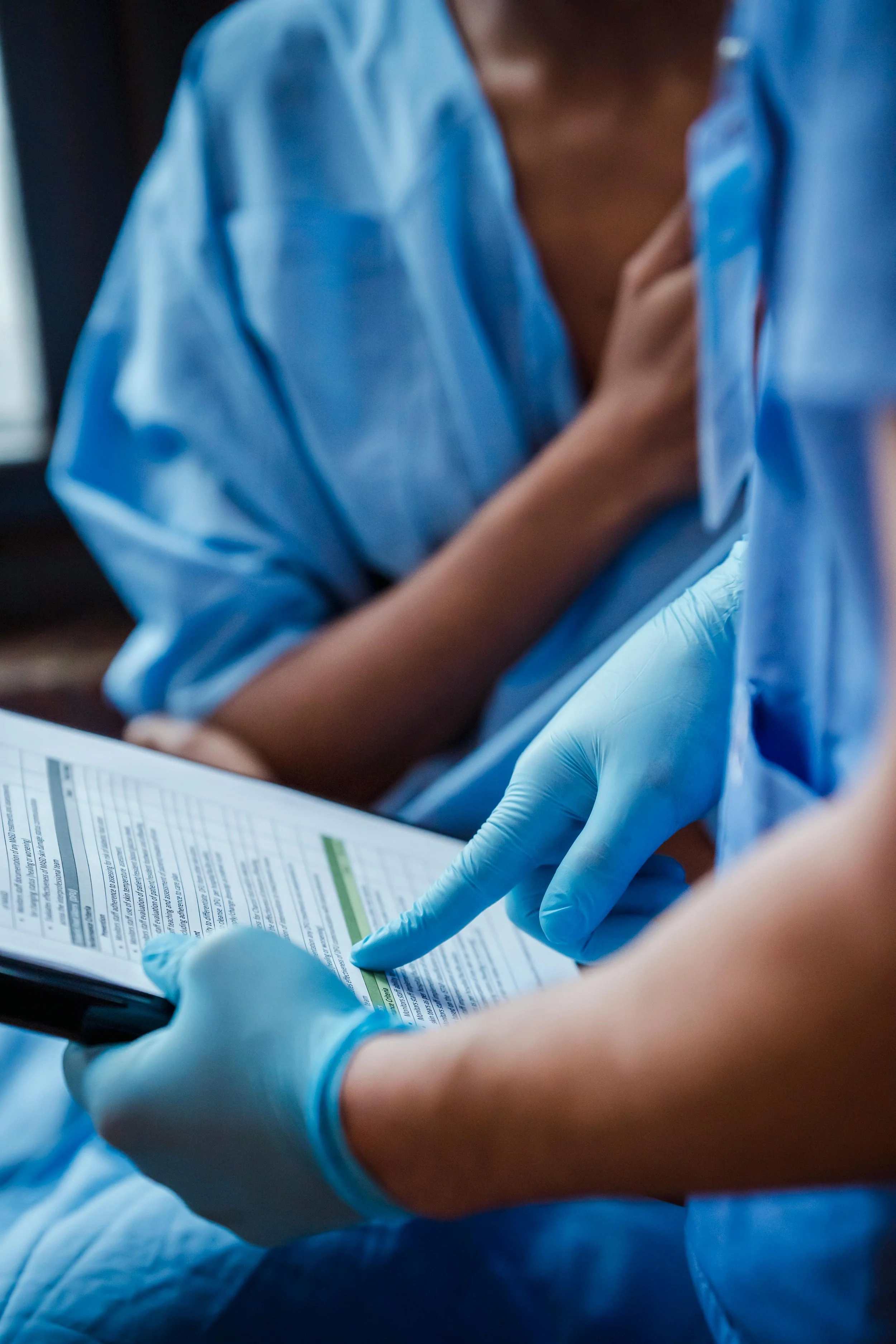 A healthcare professional wearing gloves shows a patient medical test or report on electronic device or paper.