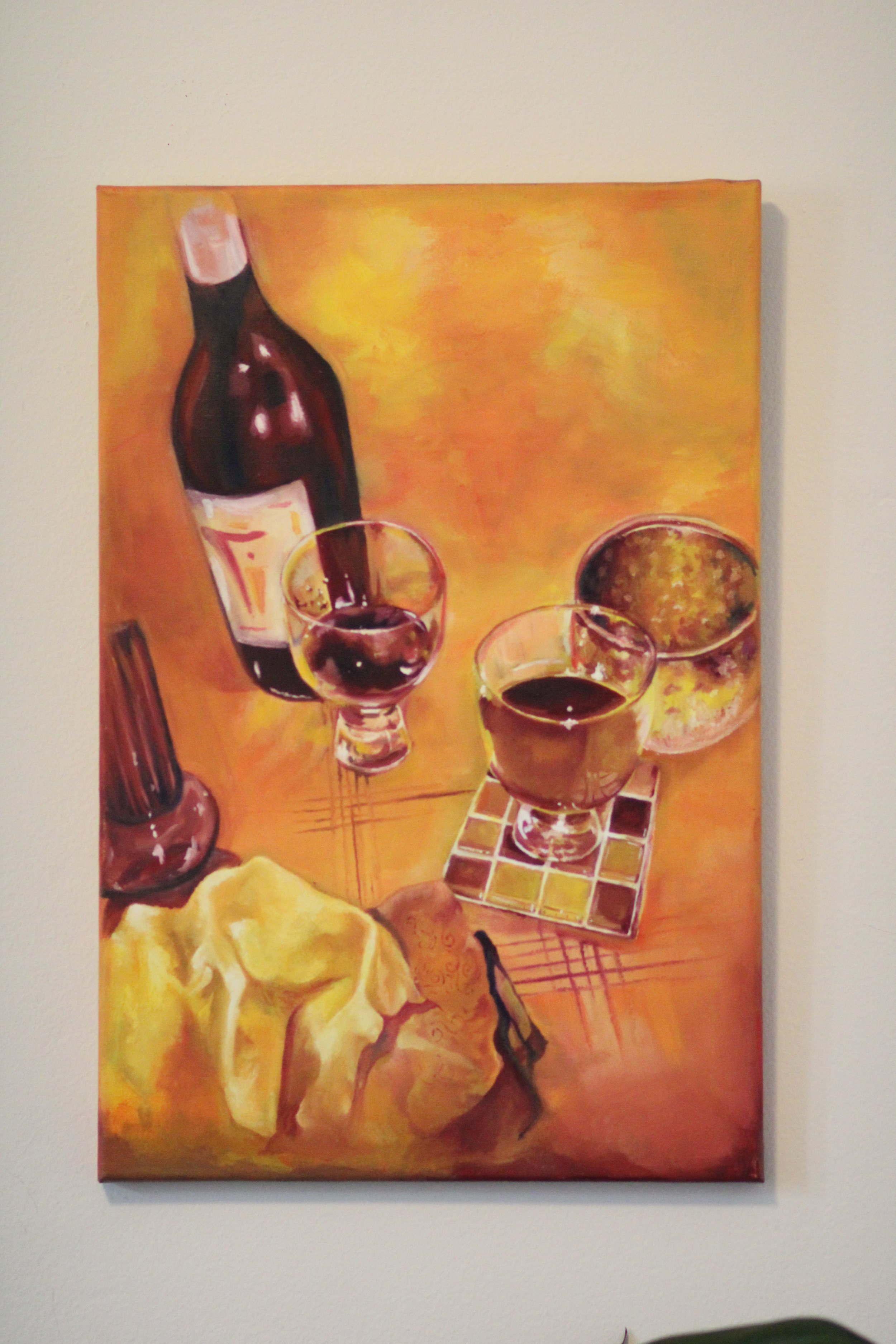 Painting of wine bottles, two glasses of red wine, a bowl of lemon slices, and a yellow cloth on a warm-toned table.