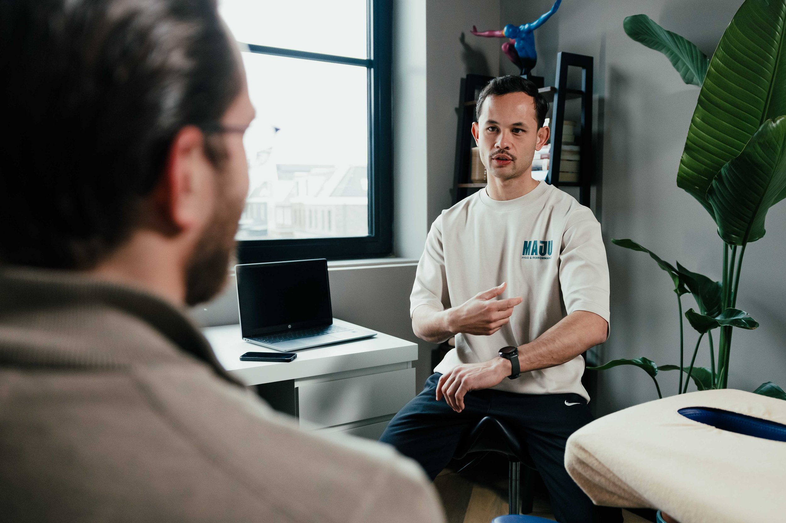 Fysiotherapeut in gesprek met patiënt tijdens intake bij MAJU Fysio & Performance in Weesp