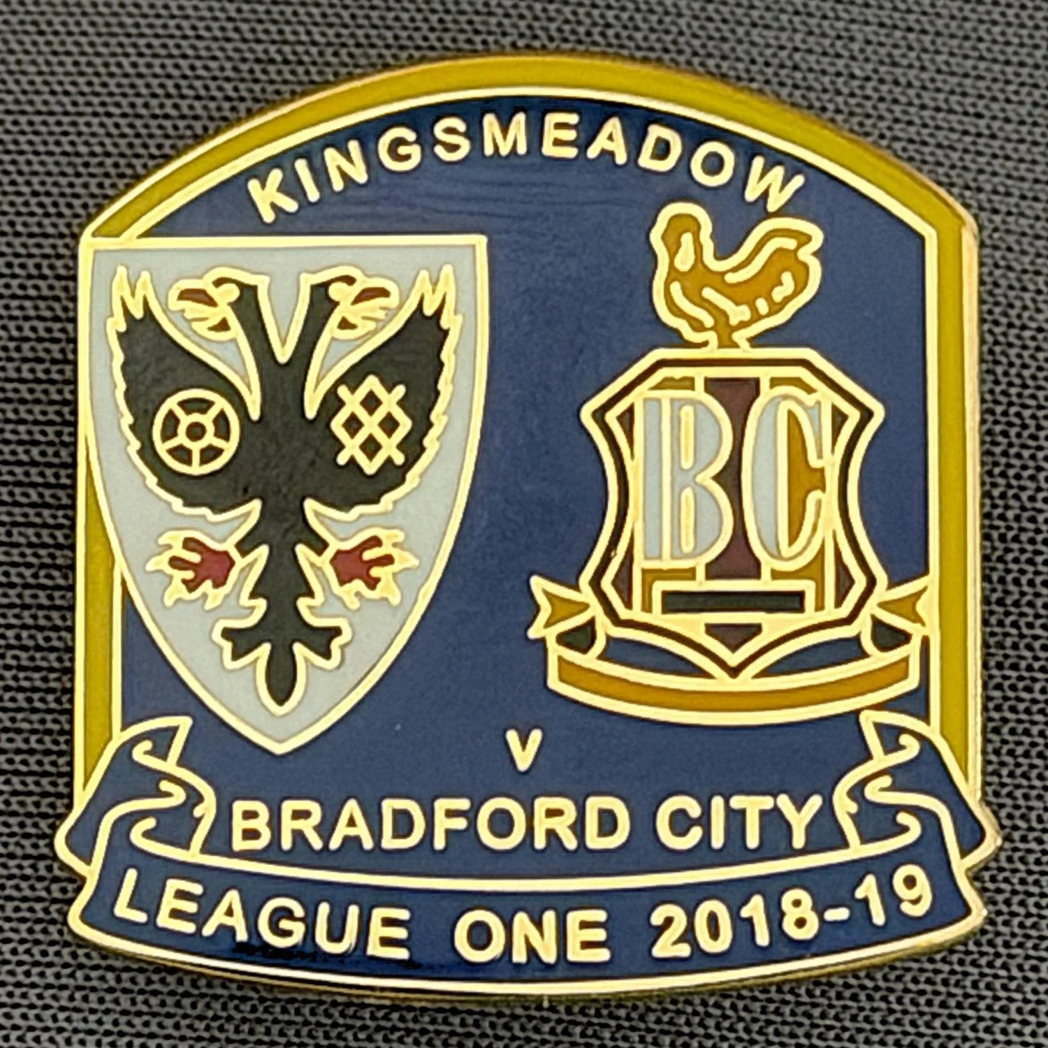 Reference Number: BCOFIX114
Size: H 25.6 mm x W 25 mm
Pin Type: Rubber Clutch
Plating: Gold
Value: £5
Manufacturer: Terry's Badges
Comments: A.F.C. Wimbledon v Bradford City, League One 2018/19