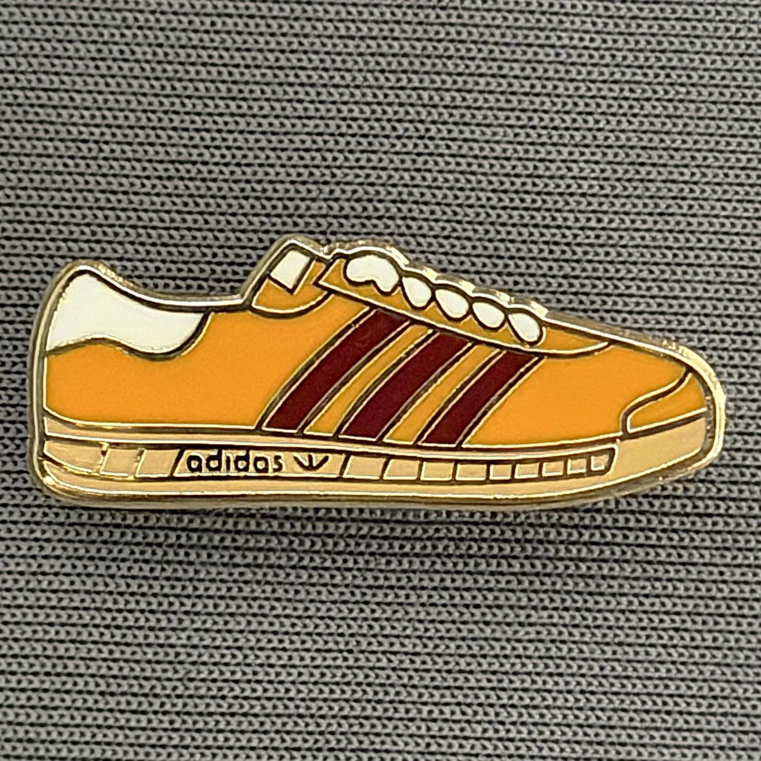 Reference Number: BCUN046
Size: H 9.9 mm x W 24.8 mm
Pin Type: Brooch Pin
Plating: Gold
Value: £4
Manufacturer: Unknown
Comments: Amber, Claret & White Trainer, Small Version