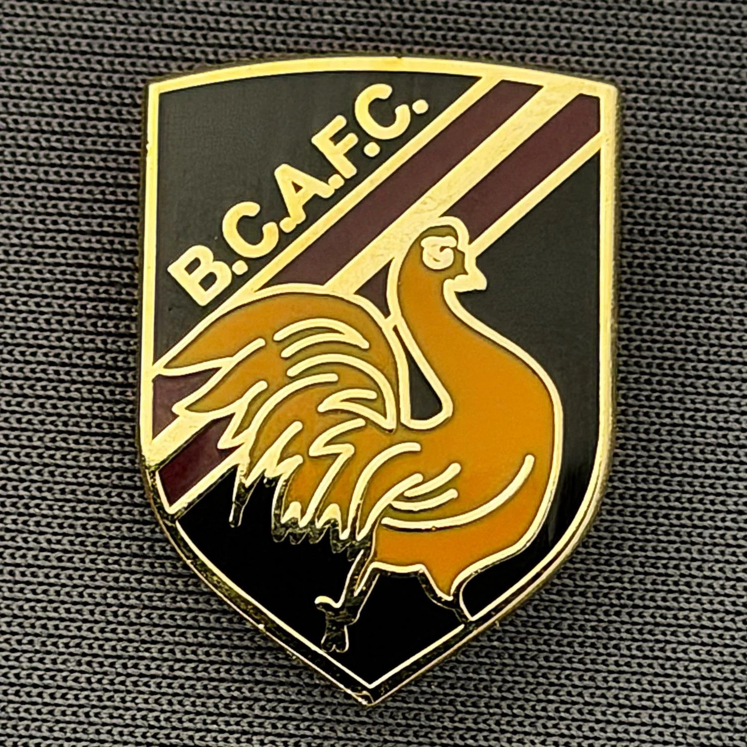 Reference Number: BCBAN053
Size: H 22.9 mm x W 16.8 mm
Pin Type: Brooch Pin
Plating: Gold
Value: £6
Manufacturer: Unknown
Comments: Black, Claret & Amber Bantam Shield, Small Version 