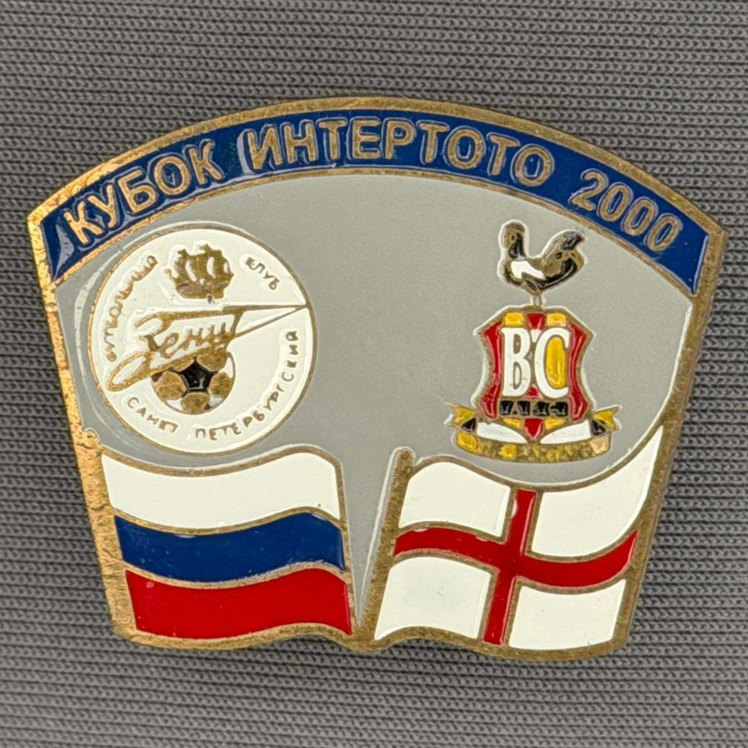 Reference Number: BCRUS032
Size: H 26 mm x W 32.3 mm
Pin Type: Metal Clutch
Plating: Antique Gold
Value: £12
Manufacturer: Unknown
Comments: Zenit St. Petersburg Inter Toto Cup, Mid Blue Top, Grey Background