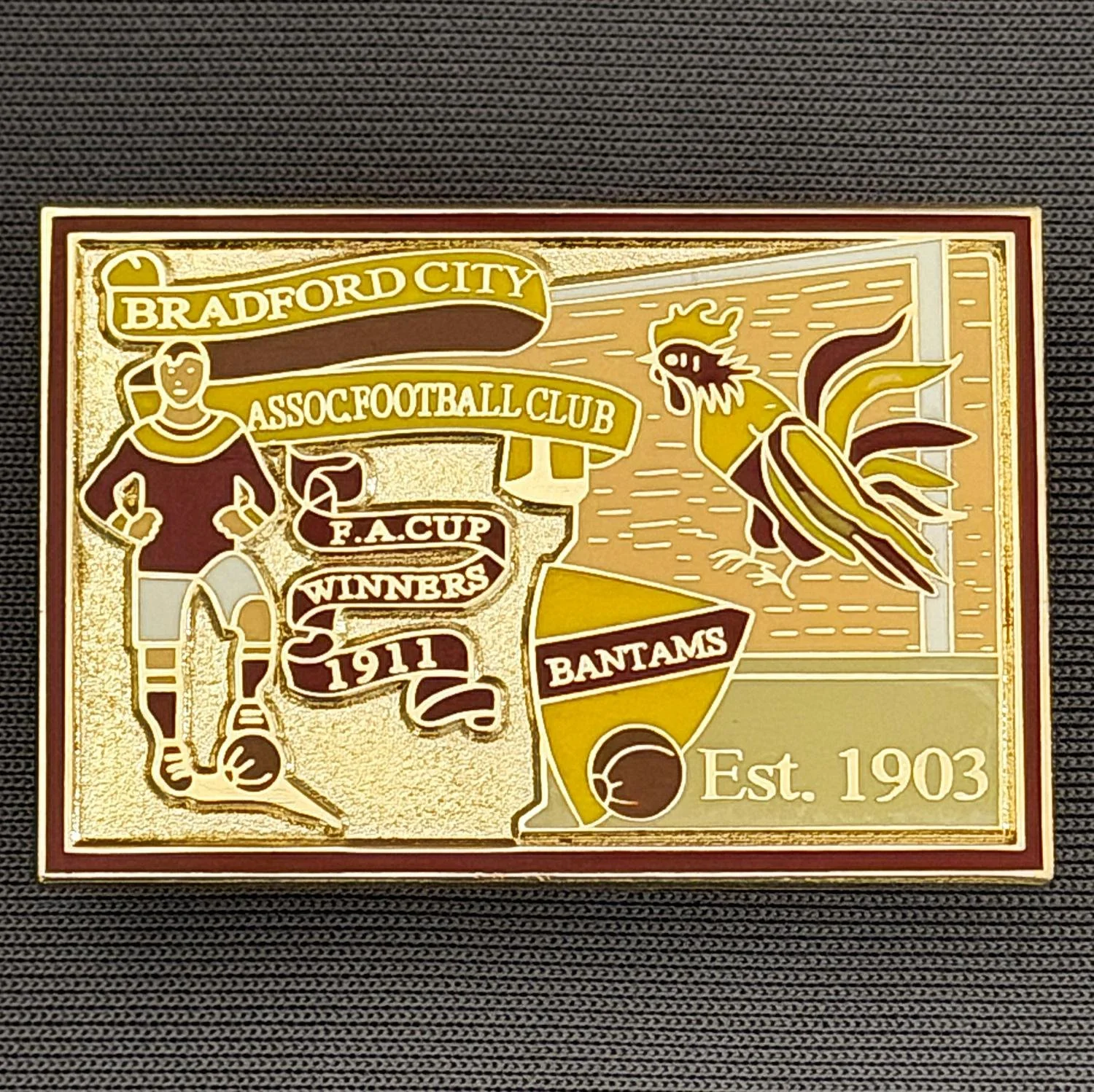 Reference Number: BCFAC029
Size: H 26.4 mm x W 38.4 mm
Pin Type: Double Metal Clutch
Plating: Gold
Value: £6
Manufacturer: Unknown
Comments: Bradford City Cup Winners 1911, Amber, Claret & Gold Version