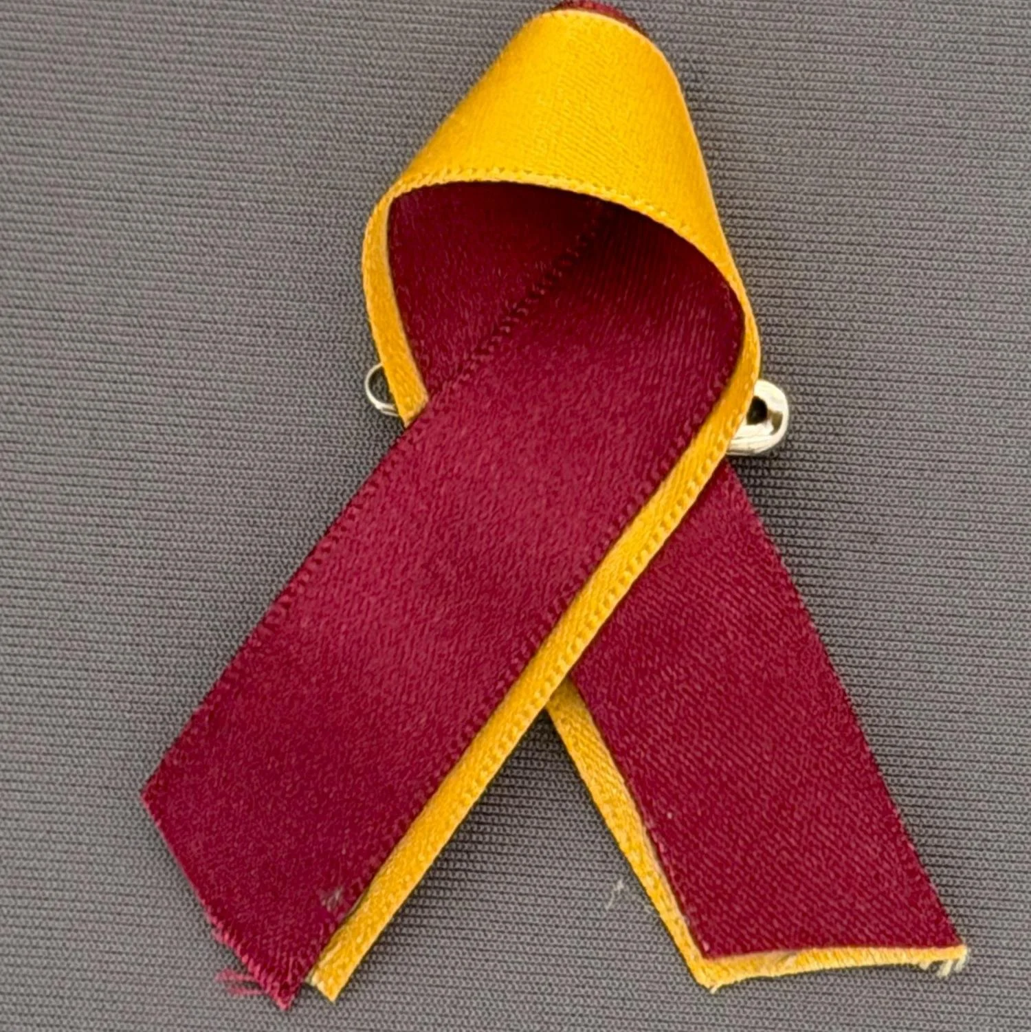 Reference Number: BCFIR023
Size: H 60 mm x W 50 mm
Pin Type: Safety Pin
Plating: N/A
Value: £5
Manufacturer: Bradford City Ribbons
Comments: Claret and Amber fabric ribbon produced by Georgia Thornton to raise money for PSBRU
