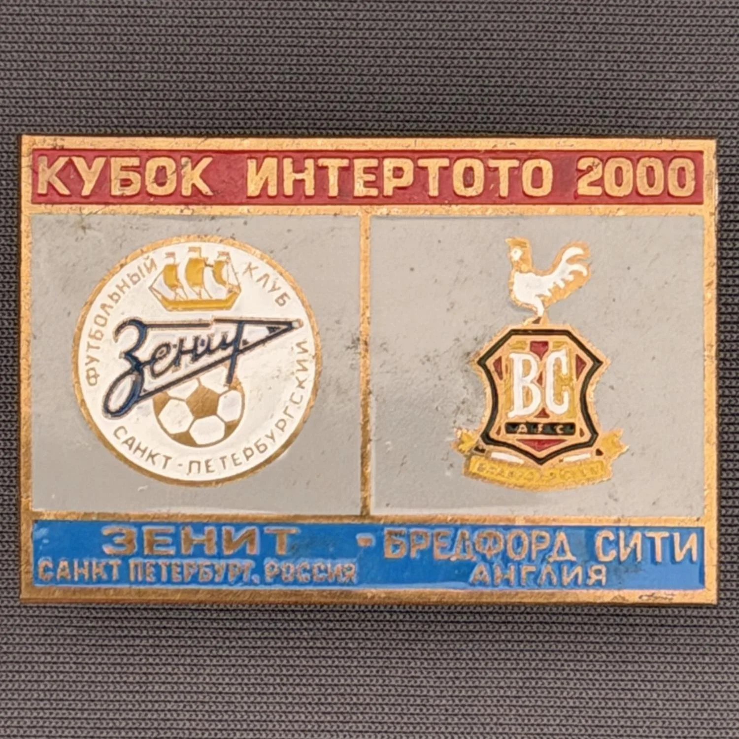 Reference Number: BCRUS019
Size: H 29.6 mm x W 44.6 mm
Pin Type: Metal Clutch
Plating: Antique Gold
Value: £12
Manufacturer: Unknown
Comments: Zenit St. Petersburg Inter Toto Cup, Red Top, Grey Middle, Mid Blue Bottom