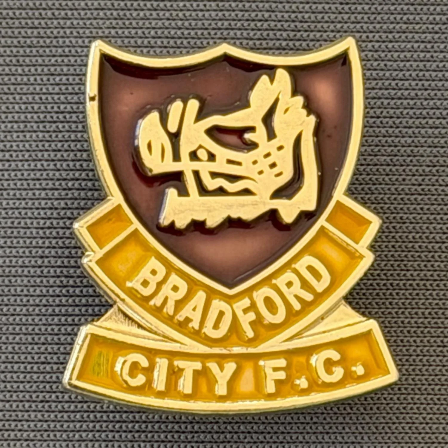 Reference Number: BCBOH054
Size: H 22.8 x W 20.4 mm
Pin Type: Brooch Pin
Plating: Gold
Value: £6
Manufacturer: Unknown
Comments: Claret & Amber Boar's Head Shield