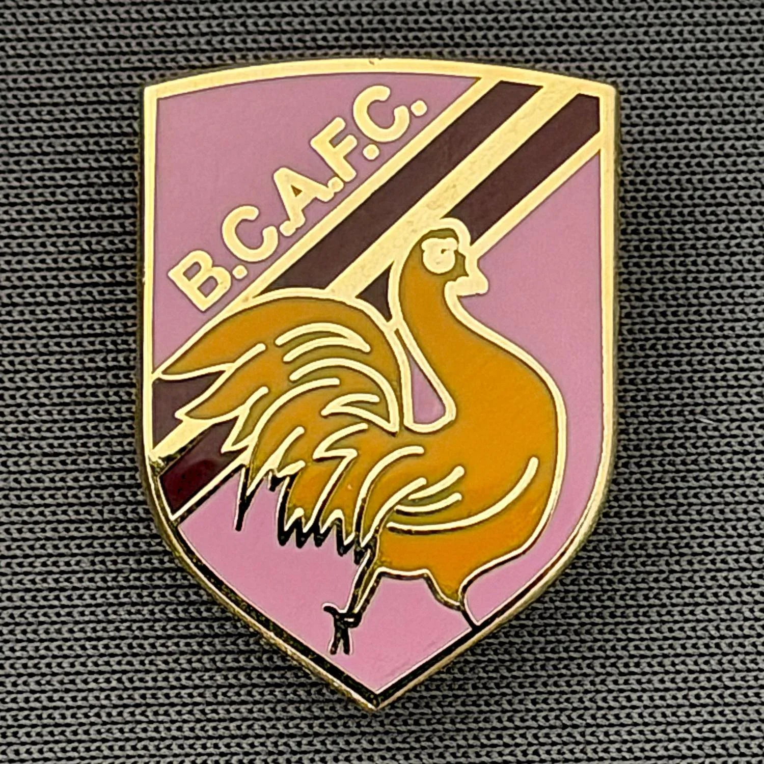 Reference Number: BCBAN055
Size: H 22.9 mm x W 16.8 mm
Pin Type: Brooch Pin
Plating: Gold
Value: £6
Manufacturer: Unknown
Comments: Pink, Claret & Amber Bantam Shield, Small Version 
