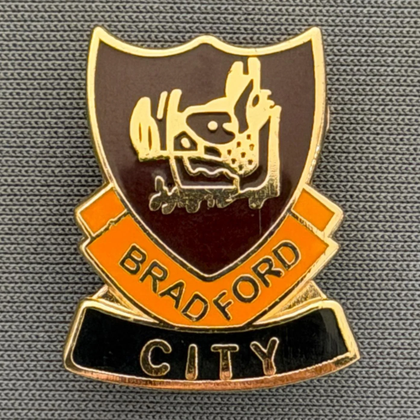 Reference Number: BCBOH063
Size: H 22 x W 18.1 mm
Pin Type: Brooch Pin
Plating: Gold
Value: £6
Manufacturer: Unknown
Comments: Claret, Amber & Black  Boar's Head Shield