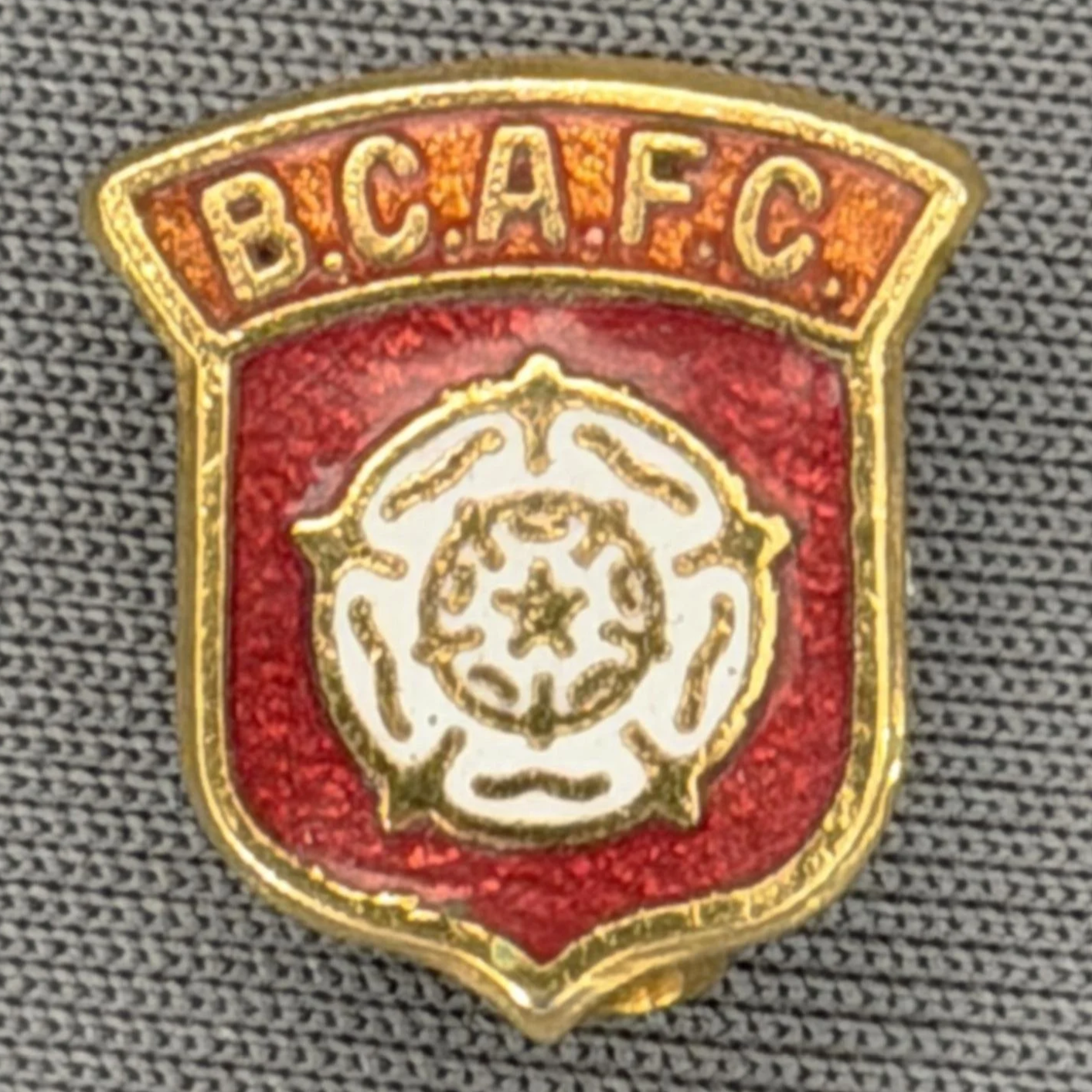 Reference Number: BCYR002
Size: H 14.5 mm x W 13.3 mm
Pin Type: Brooch Pin
Plating: Gold
Value: £8
Manufacturer: Unknown
Comments: Small Claret & Amber Yorkshire Rose Shield
