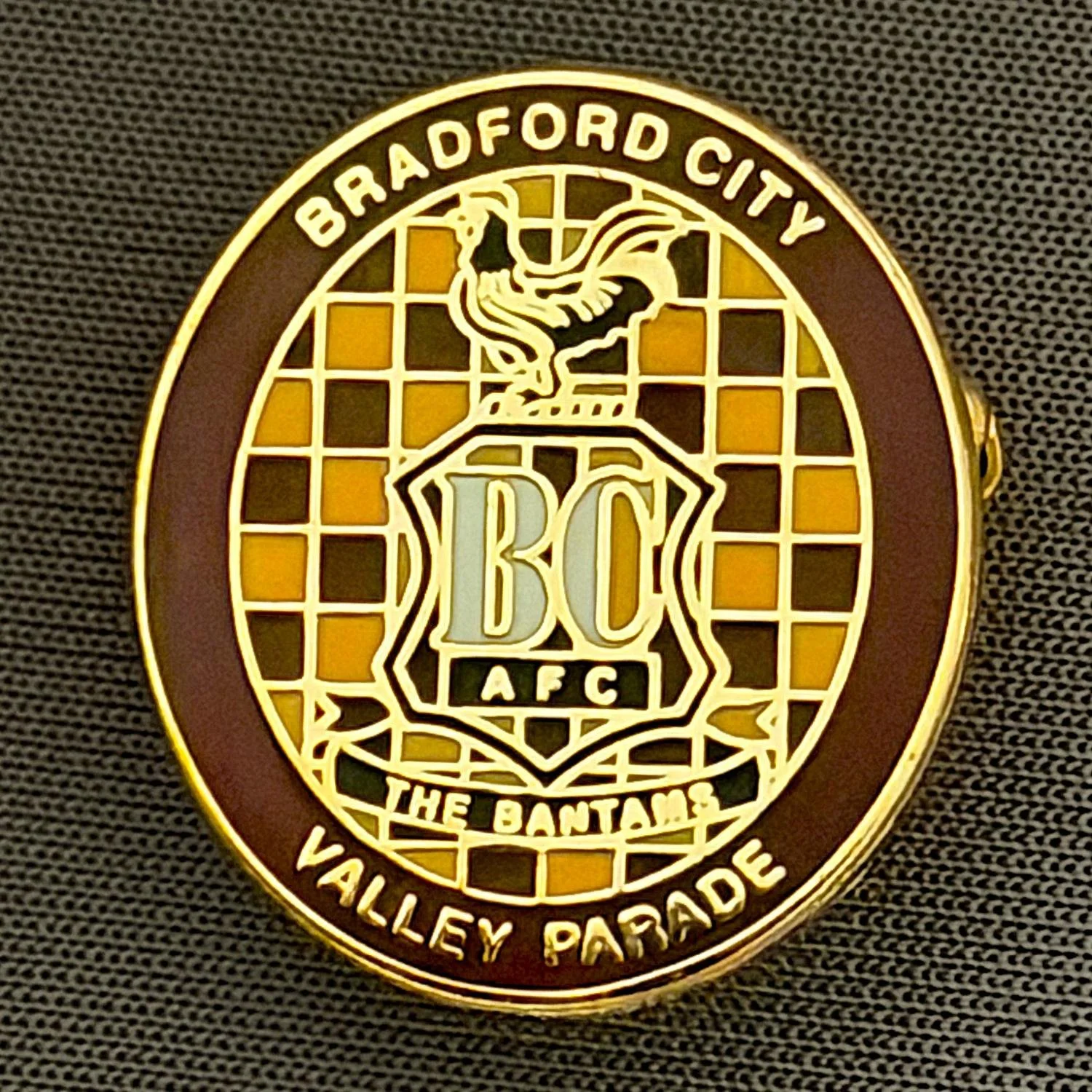 Reference Number: BCC&L098
Size: H 22.6 mm x 20.3  mm
Pin Type: Brooch Pin
Plating: Gold
Value: £6
Manufacturer: Unknown
Comments: Oval Claret & Amber Check City Crest
