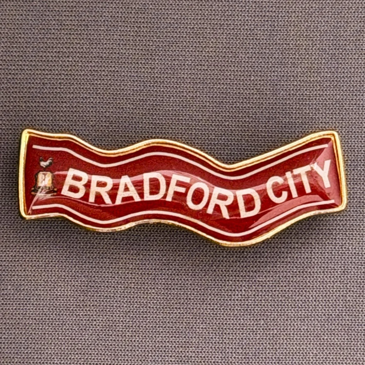 Reference Number: BCSCA012
Size: H 13.8 mm x W 39.7 mm
Pin Type: Brooch Pin
Plating: Gold
Value: £4
Manufacturer: Unknown
Comments: Claret & White Bradford City Scarf with City Logo