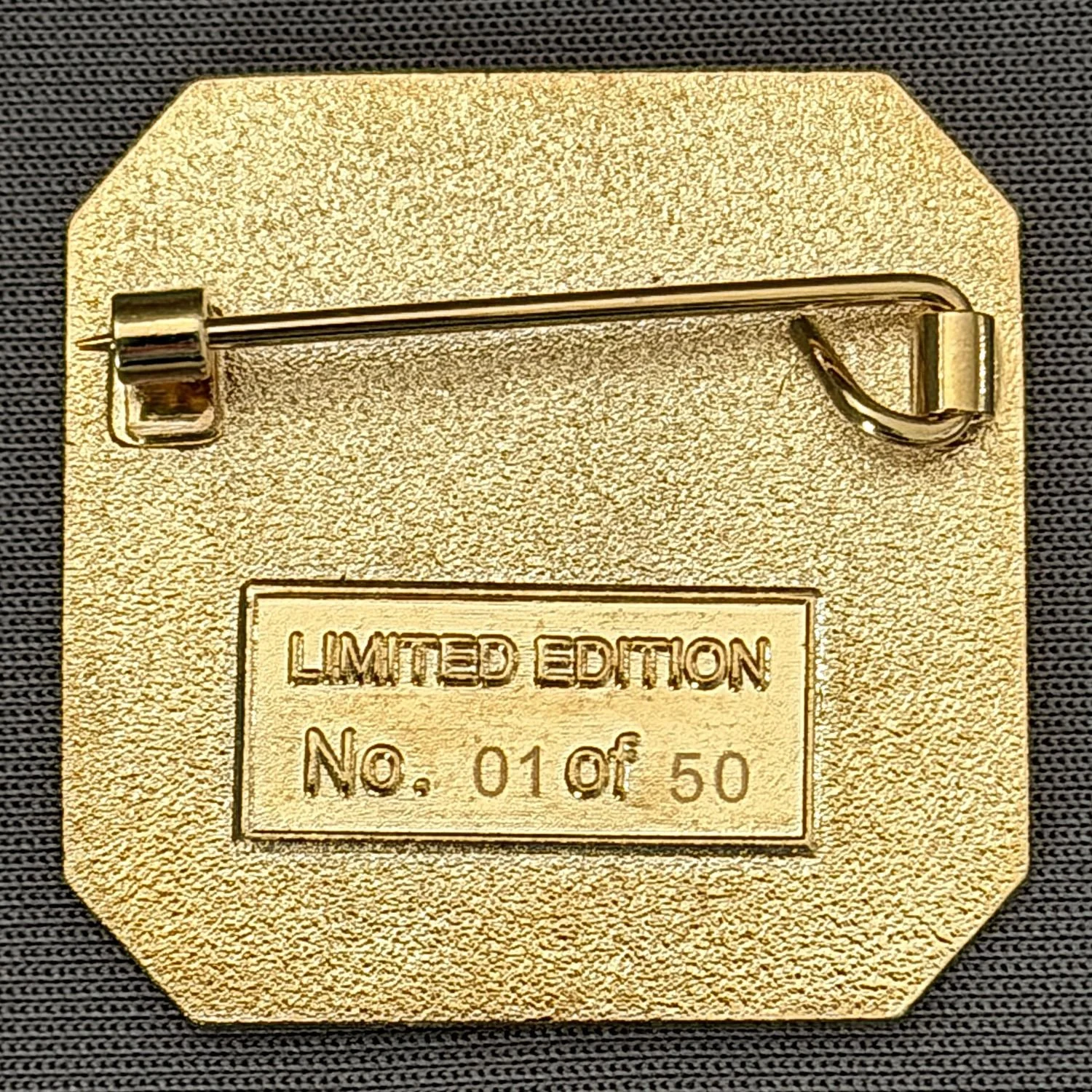 Gold-colored limited edition lapel pin with a safety pin fastening on the back, engraved with the number 010 of 50 and the text 'Limited Edition'.