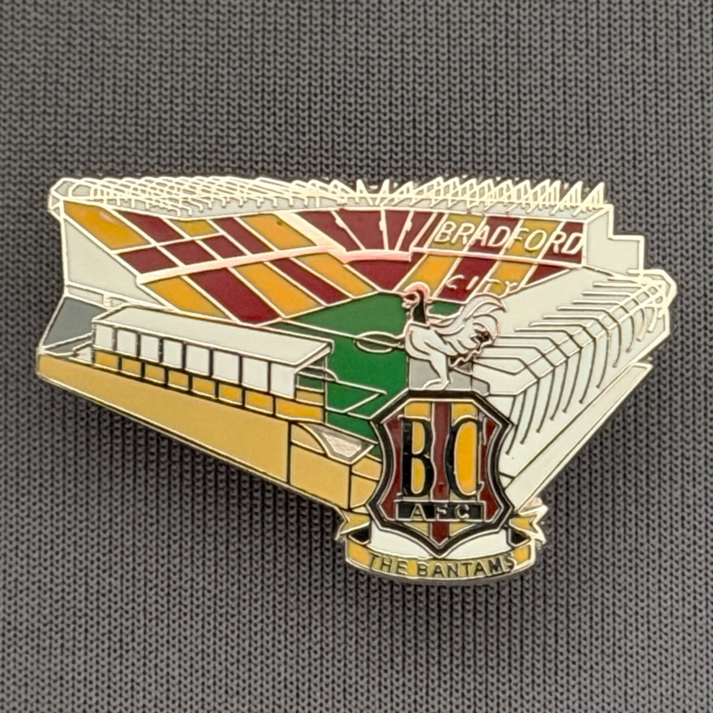 Reference Number: BCVP023
Size: H 20.5 mm x W 32.1 mm
Pin Type: Metal Clutch
Plating: Black Nickel
Value: £4
Manufacturer: Dan Lloyd
Comments: Valley Parade Stadium with Coloured City Logo