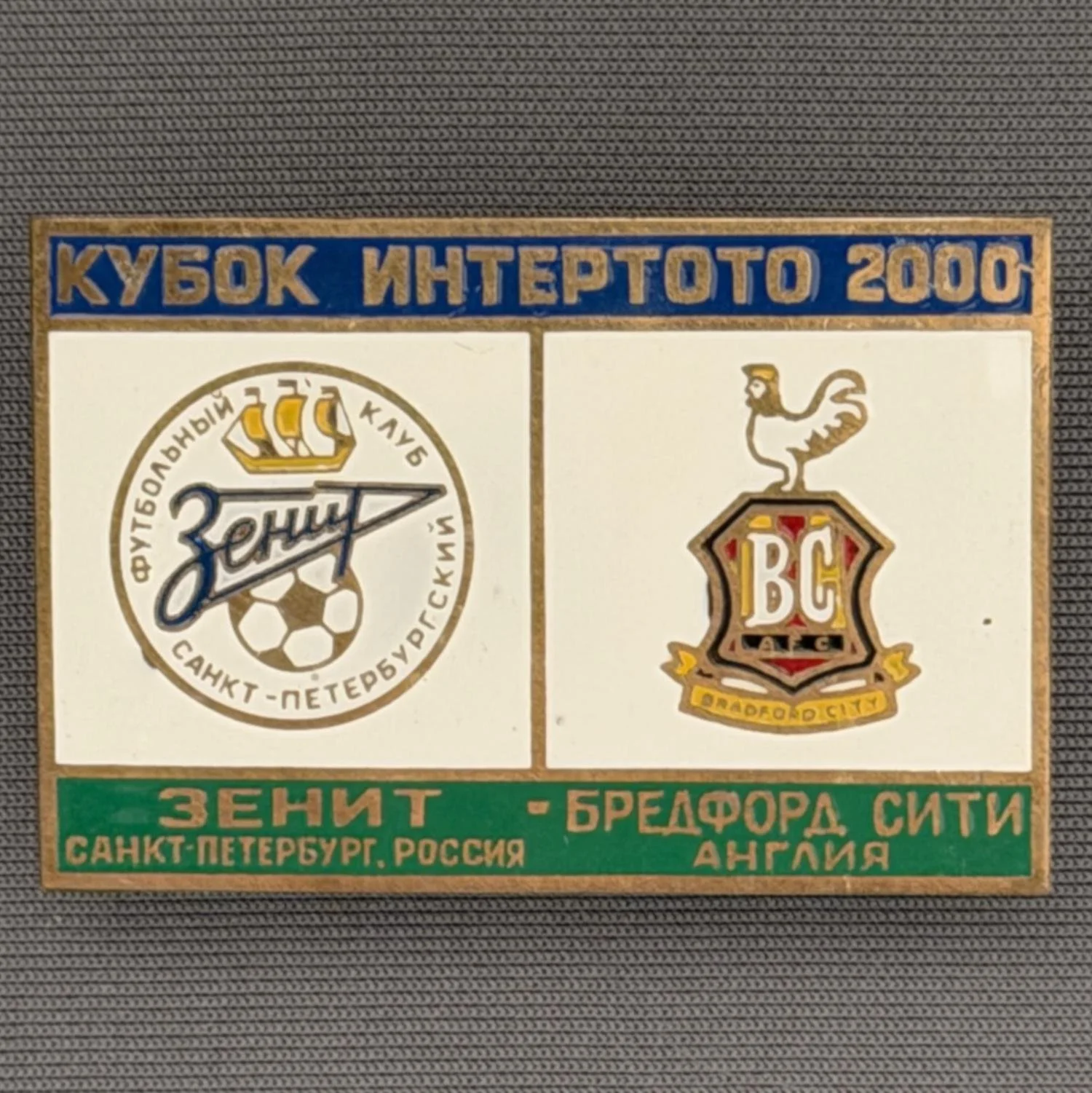Reference Number: BCRUS012
Size: H 29.6 mm x W 44.6 mm
Pin Type: Metal Clutch
Plating: Antique Gold
Value: £12
Manufacturer: Unknown
Comments: Zenit St. Petersburg Inter Toto Cup, Blue Top, White Middle, Green Bottom