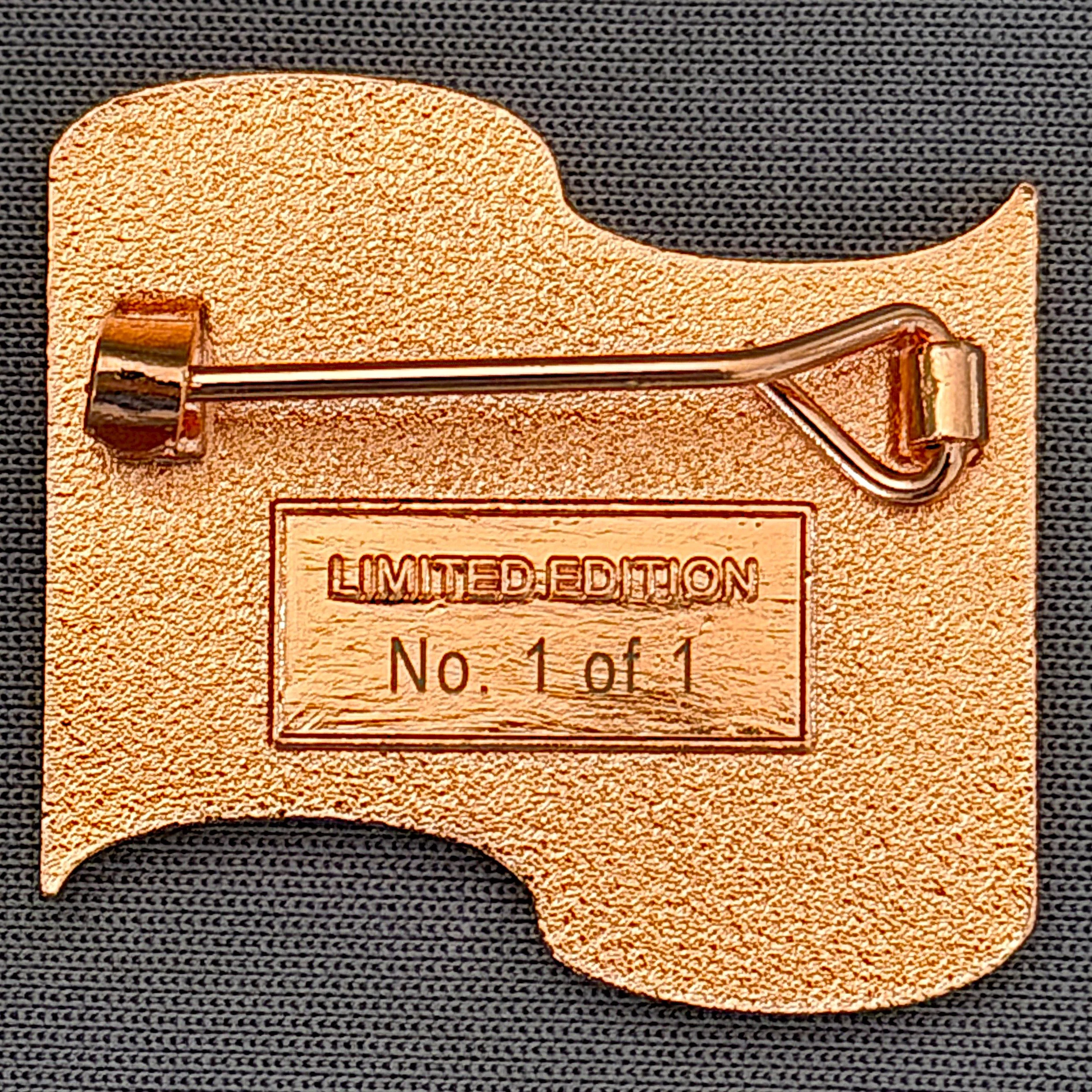A limited edition orange sticker of a stylized capital letter 'Q' with a metallic finish.
