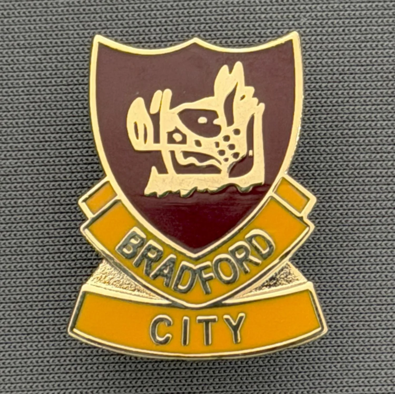 Reference Number: BCBOH059
Size: H 23.8 x W 19.1 mm
Pin Type: Brooch Pin
Plating: Gold
Value: £6
Manufacturer: Unknown
Comments: Claret & Amber Boar's Head Shield