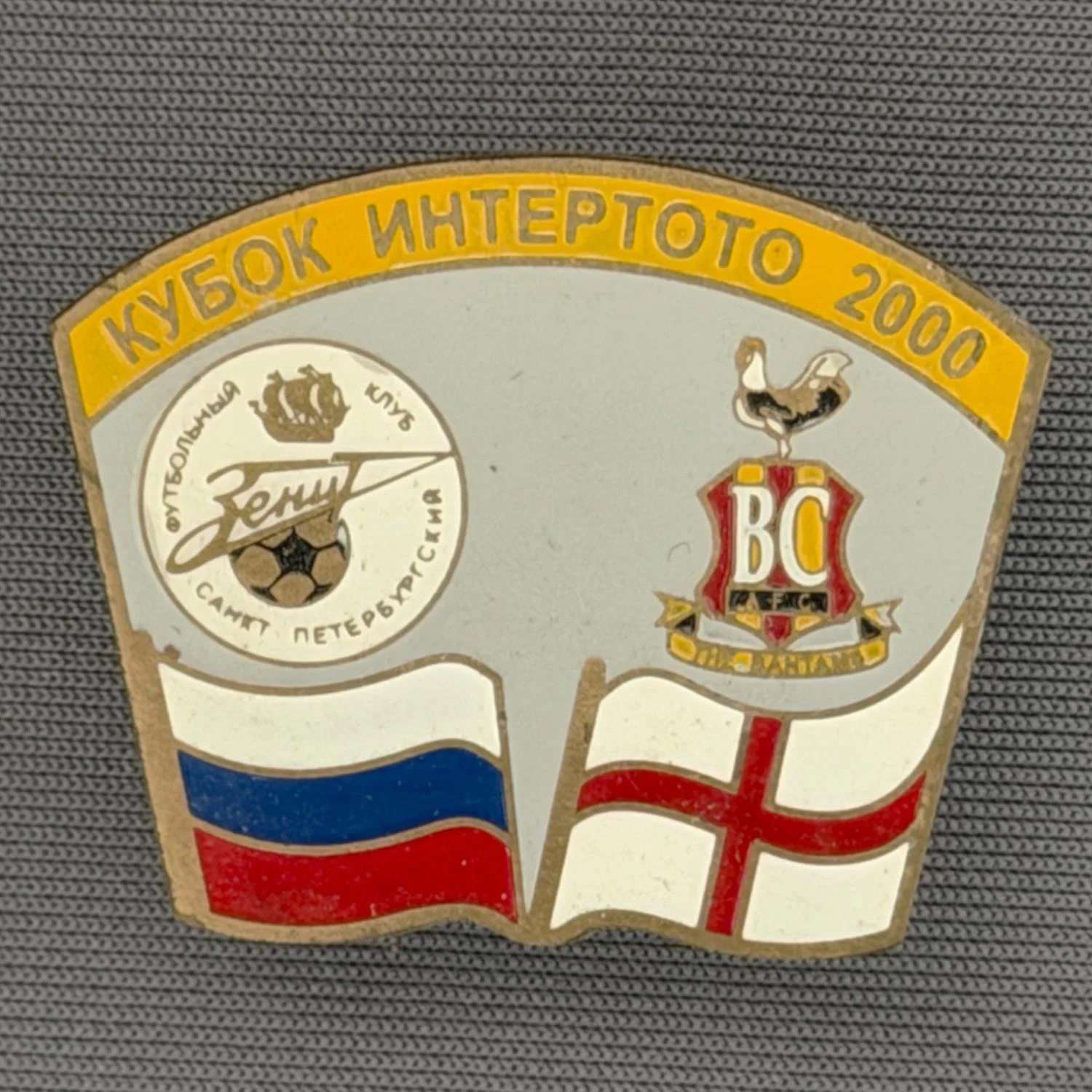 Reference Number: BCRUS035
Size: H 26 mm x W 32.3 mm
Pin Type: Metal Clutch
Plating: Antique Gold
Value: £12
Manufacturer: Unknown
Comments: Zenit St. Petersburg Inter Toto Cup, Yellow Top, Grey Background
