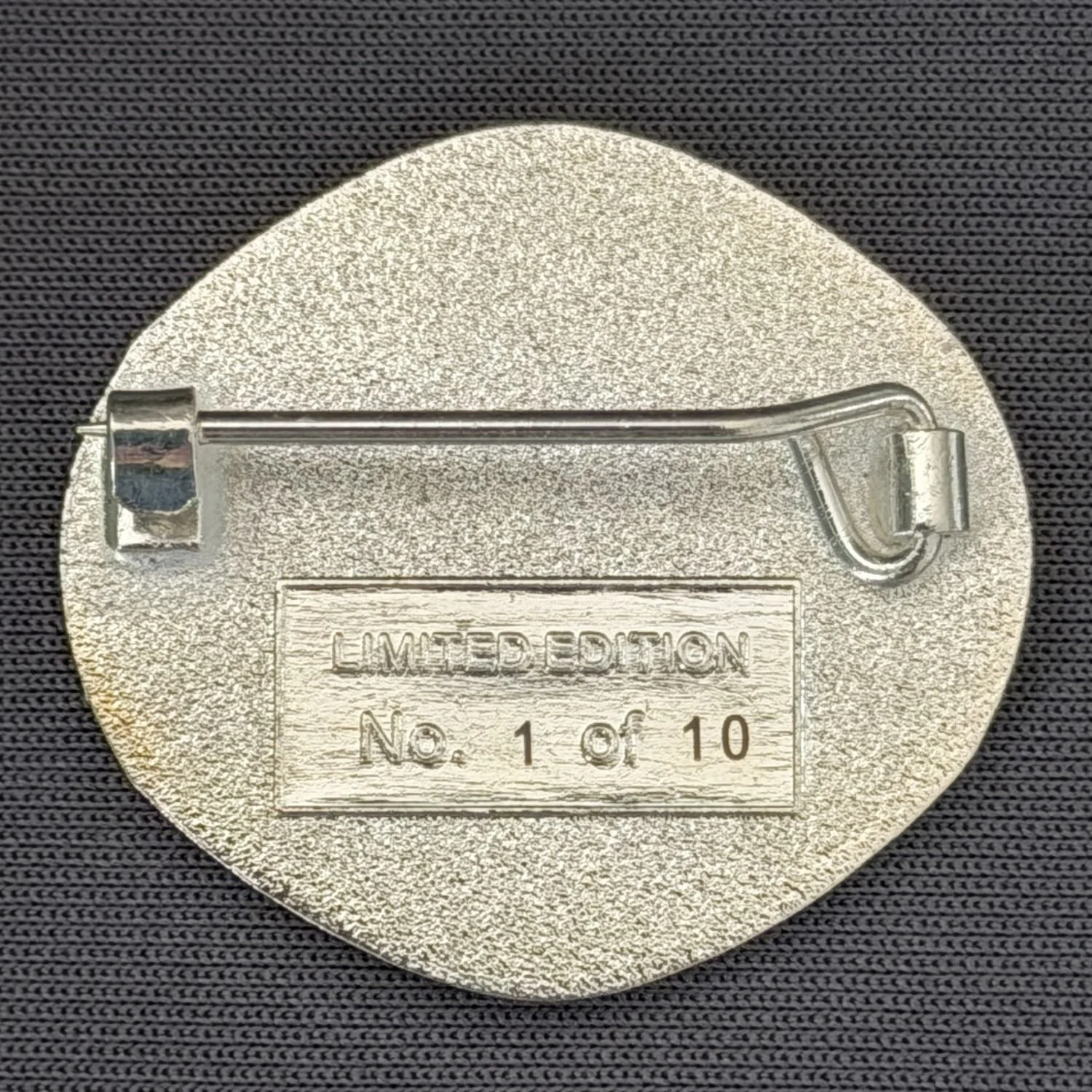 Close-up of a limited edition badge with a pin on the back, engraved with 'Limited Edition.'