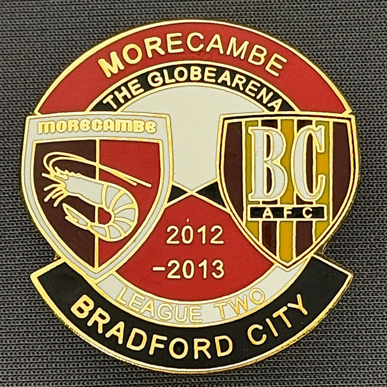 Reference Number: BCOFIX142
Size: H 32.4 mm x W 30.5 mm
Pin Type: Double Rubber Clutch
Plating: Gold
Value: £5
Manufacturer: Unknown
Comments: Morecambe v Bradford City  League Two 2012/13, Red & Black Version 