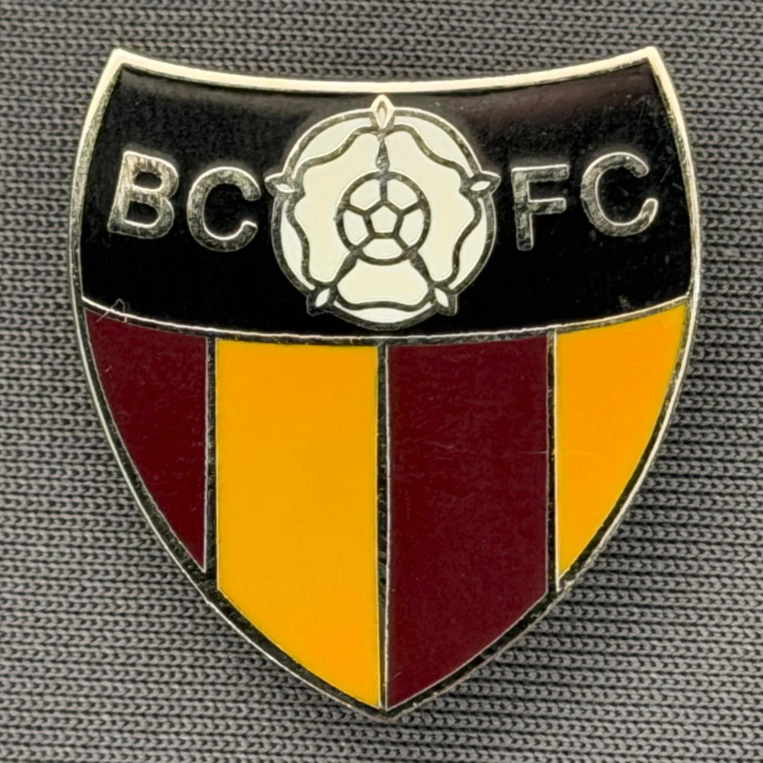 Reference Number: BCYR022
Size: H 25 mm x W 22.8 mm
Pin Type: Brooch Pin
Plating: Gold
Value: £6
Manufacturer: Unknown
Comments: BCFC Yorkshire Rose Black, Claret & Amber Shield. Larger version.