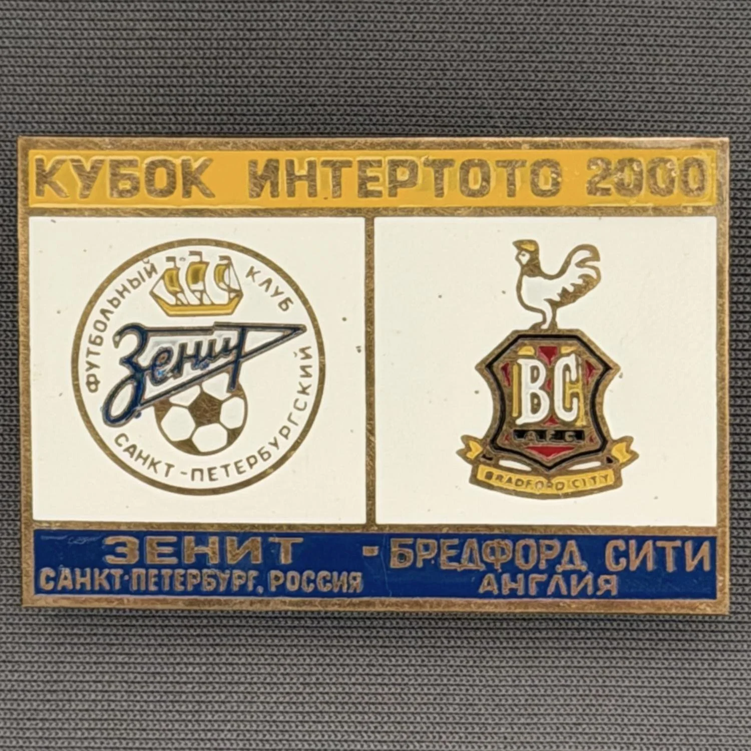 Reference Number: BCRUS014
Size: H 29.6 mm x W 44.6 mm
Pin Type: Metal Clutch
Plating: Antique Gold
Value: £12
Manufacturer: Unknown
Comments: Zenit St. Petersburg Inter Toto Cup, Yellow Top, White Middle, Blue Bottom