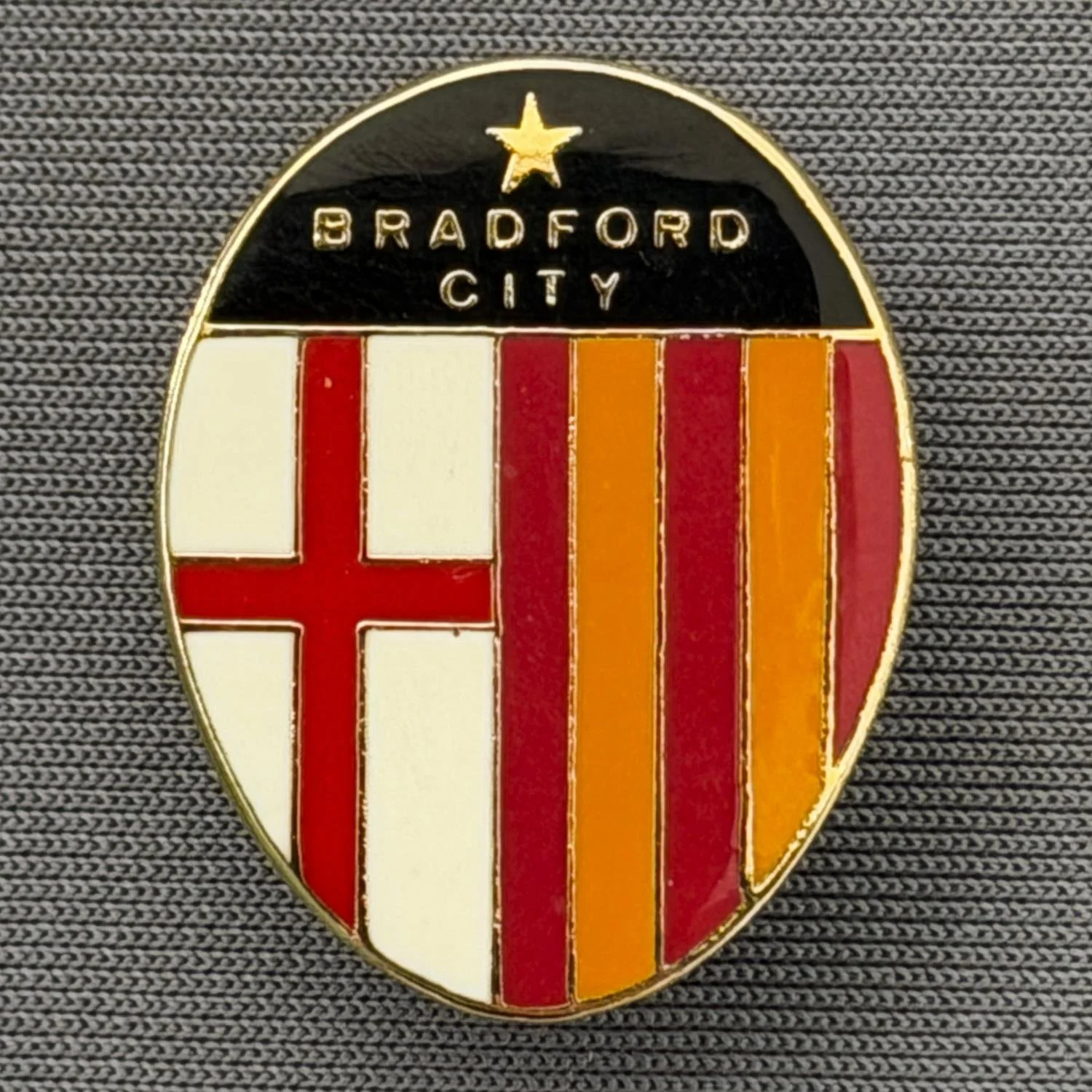 Reference Number: BCFLA017
Size: H 25 mm x W 19.5 mm
Pin Type: Brooch Pin
Plating: Gold
Value: £6
Manufacturer: Not Known
Comments: St George Flag, Claret & Amber Stripes, Bradford City, Black Version