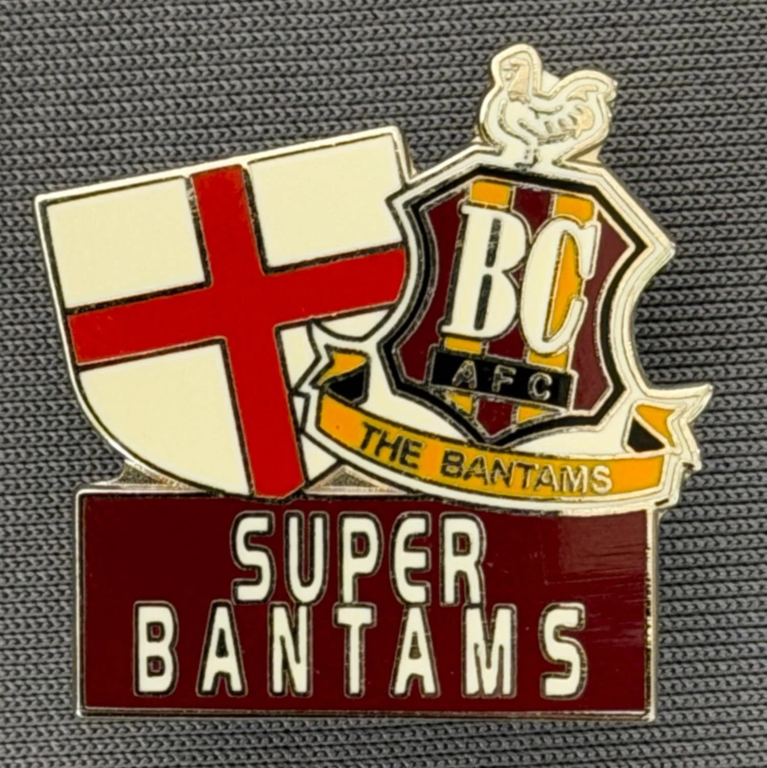 Reference Number: BCFLA012
Size: H 25 mm x W 24 mm
Pin Type: Brooch Pin
Plating: Silver
Value: £6
Manufacturer: Not Known
Comments: St George Cross Shield, City Logo & Super Bantams