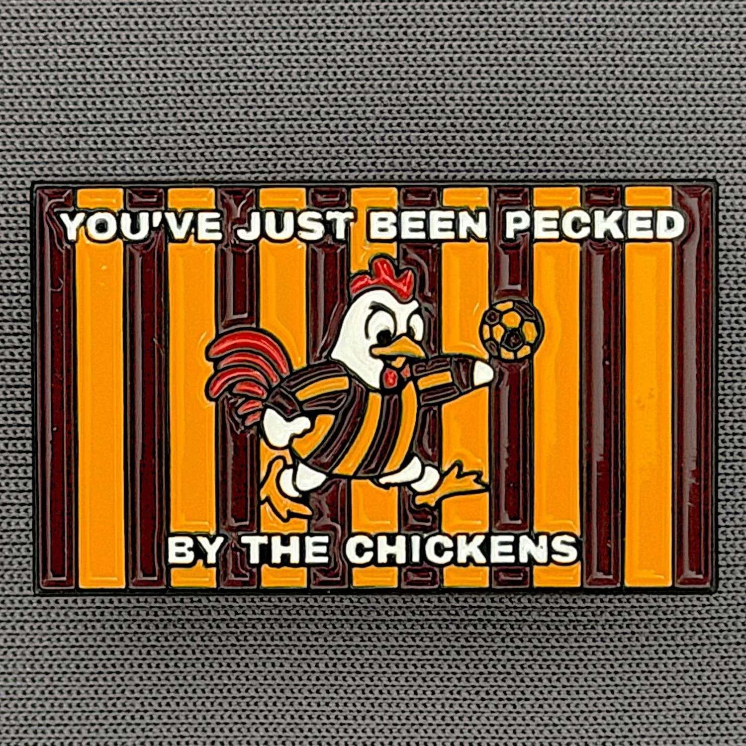 Reference Number: BCBAN068
Size: H 18.4 mm x W 30.5 mm
Pin Type: Metal Clutch
Plating: Black Nickel
Value: £6
Manufacturer: Bingley Bantams
Comments: Just Been Pecked By The Chickens 