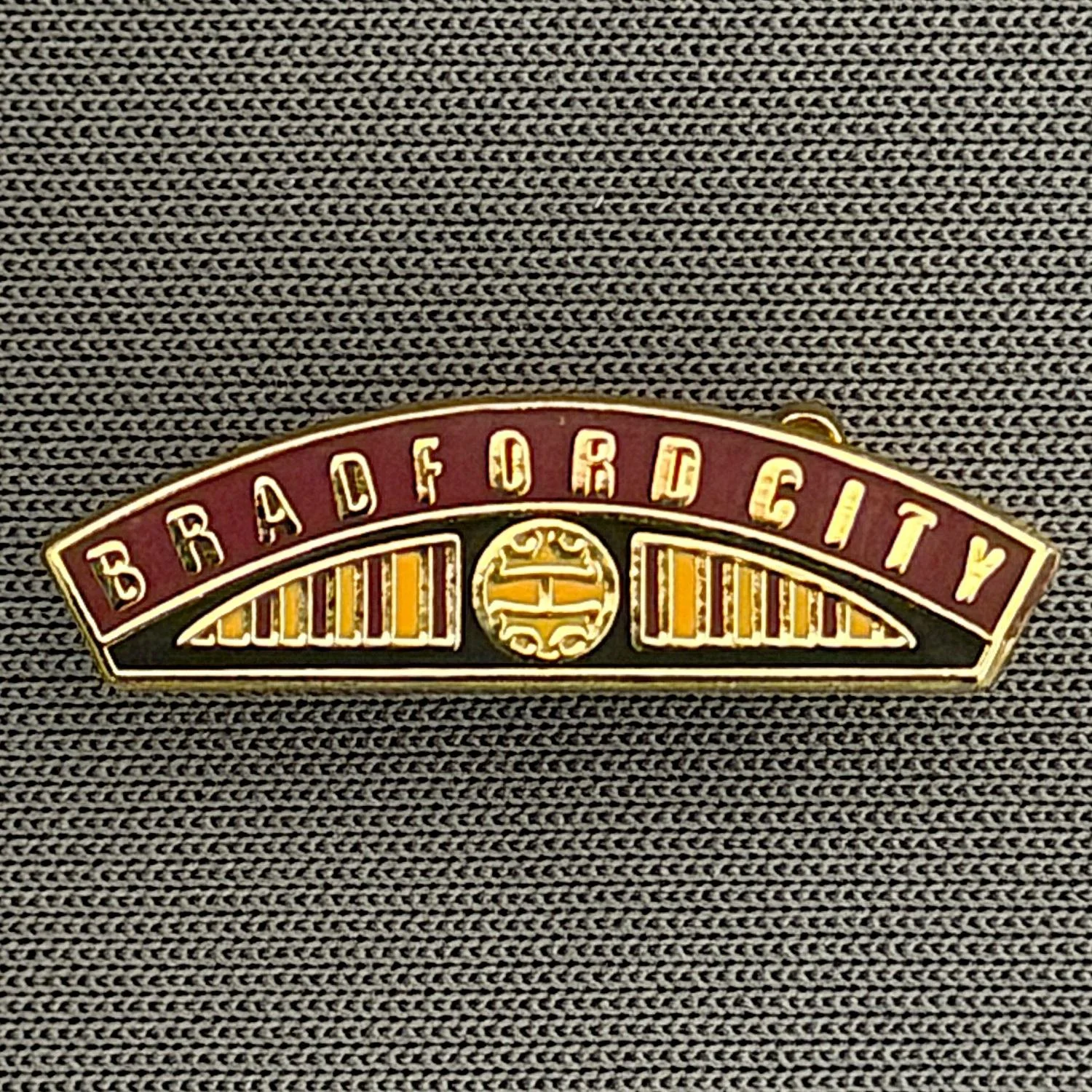 Reference Number: BCBCFC057
Size: H 6.6 mm x W 22.6 mm
Pin Type: Brooch Pin
Plating: Gold
Value: £6
Manufacturer: Unknown
Comments: Bradford City Claret & Amber Railway Engine Nameplate 