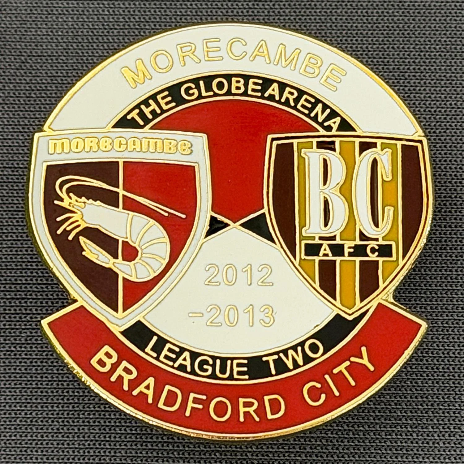 Reference Number: BCOFIX143
Size: H 32.4 mm x W 30.5 mm
Pin Type: Double Rubber Clutch
Plating: Gold
Value: £5
Manufacturer: Unknown
Comments: Morecambe v Bradford City  League Two 2012/13, White & Red Version 