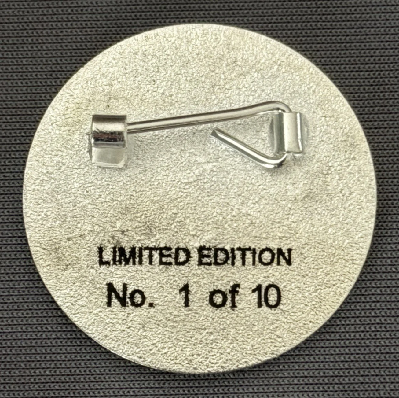 Back of a limited edition pin with a safety pin clasp, inscribed with "Limited Edition, No. 1 of 10".