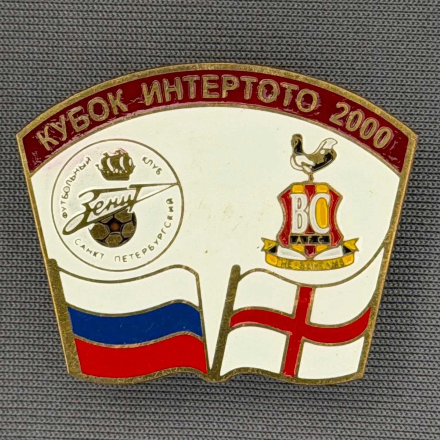 Reference Number: BCRUS025
Size: H 26 mm x W 32.3 mm
Pin Type: Metal Clutch
Plating: Antique Gold
Value: £12
Manufacturer: Unknown
Comments: Zenit St. Petersburg Inter Toto Cup, Claret Top, White Background