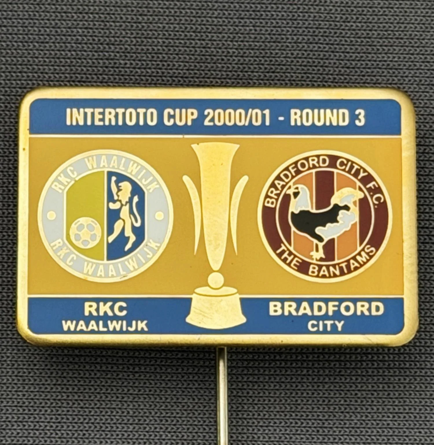 Reference Number: BCRUS043
Size: H 19.8 mm x W 30 mm
Pin Type: Metal Stick Pin
Plating: Gold
Value: £12
Manufacturer: Unknown
Comments: Inter Toto Cup, RKC Waalwijk v Bradford City, Blue & Yellow Version