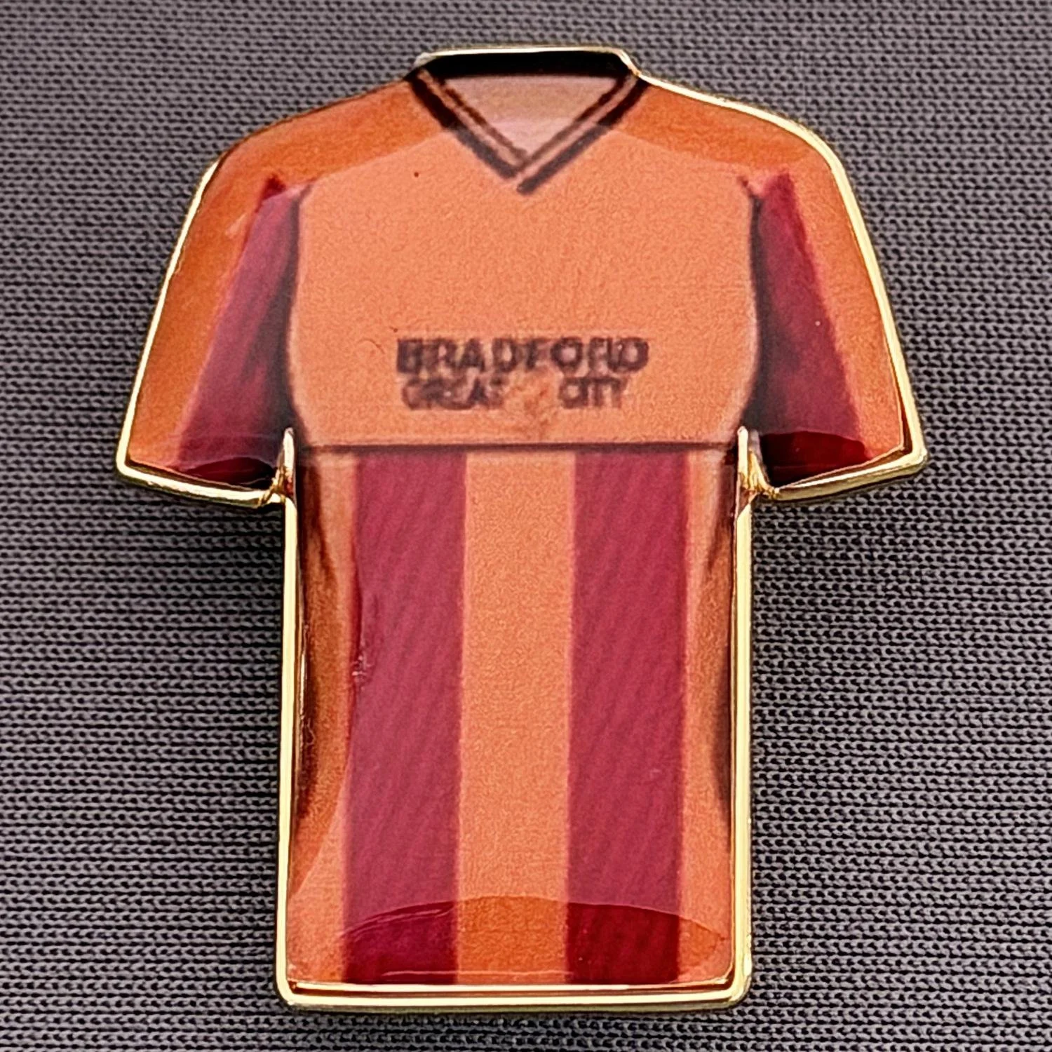 Reference Number: BCKIT092
Size: H 33 mm x W 27.1 mm
Pin Type: Metal Clutch
Plating: Gold
Value: £4
Manufacturer: Blue Badge Design
Comments: Bradford City 1987/88 Home Kit, Plastic Dome
