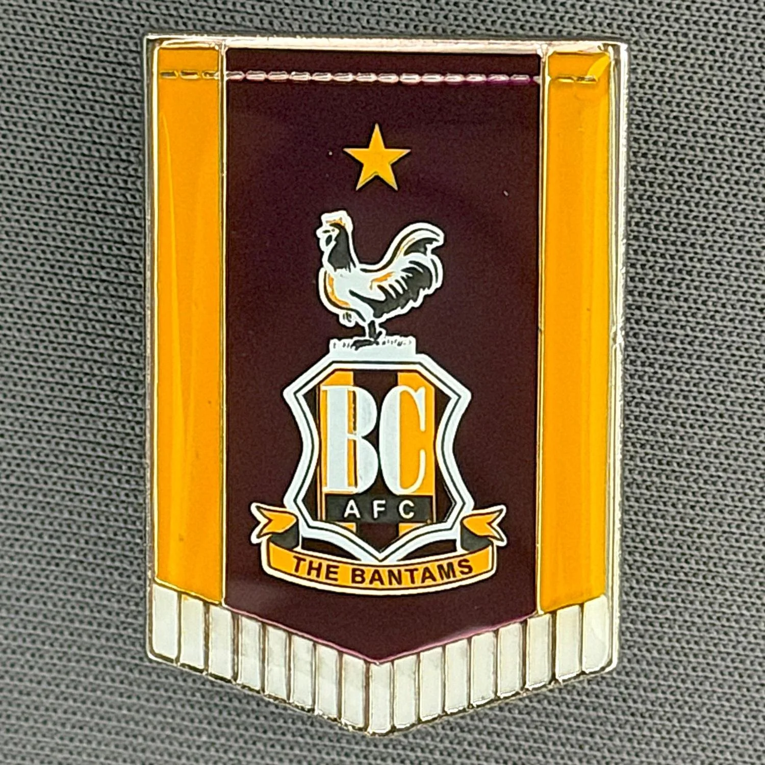 Reference Number: BCC&L166
Size: H 30 mm x 20.4 mm
Pin Type: Metal Clutch
Plating: Chrome
Value: £6
Manufacturer: Bradford City Shop
Comments: City Logo Pennant, Plastic Dome