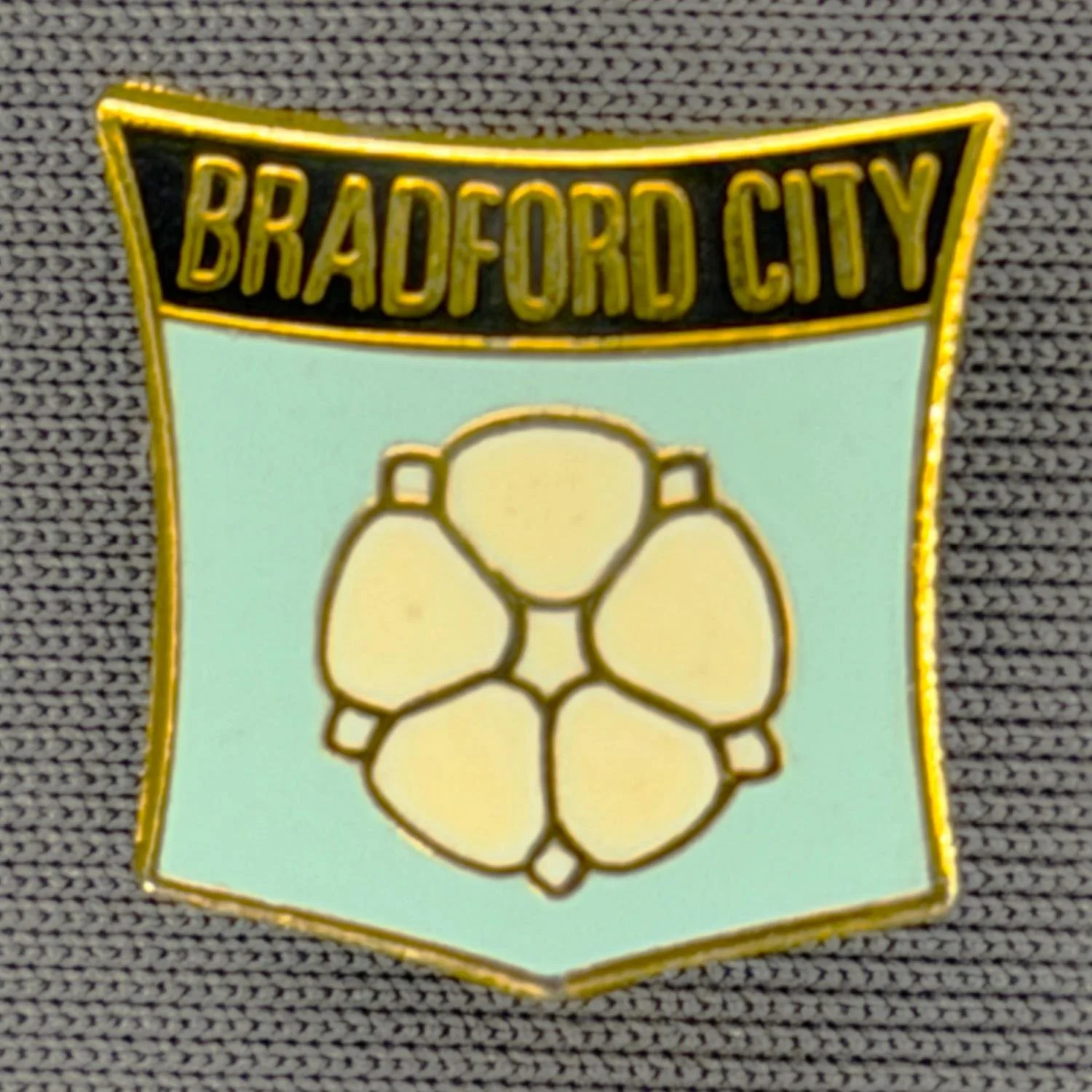 Reference Number: BCYR018
Size: H 15.6 mm x W 15.6 mm
Pin Type: Brooch Pin
Plating: Gold
Value: £8
Manufacturer: Unknown
Comments: Black & Pale Blue City Yorkshire Rose Shield