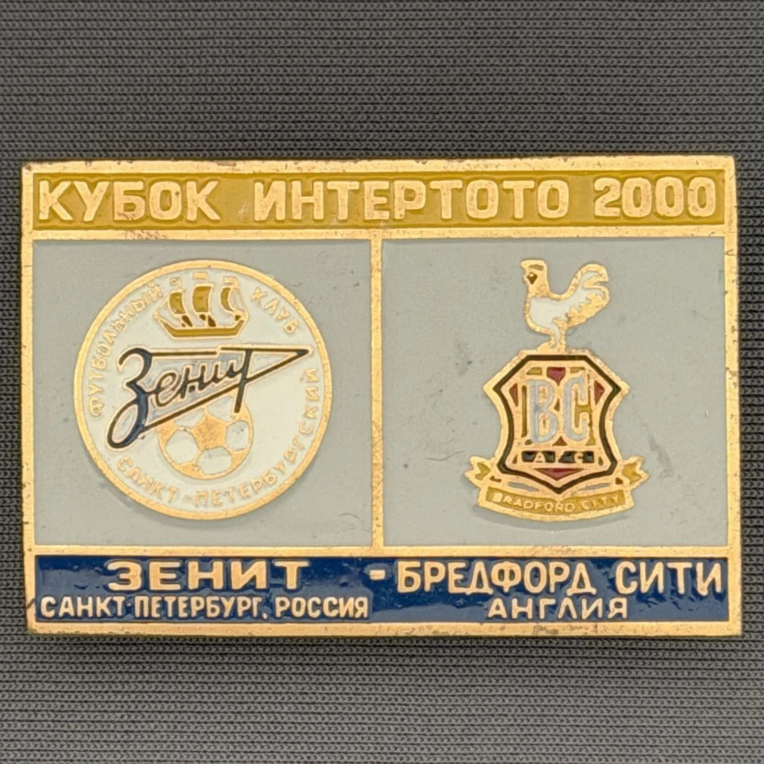 Reference Number: BCRUS023
Size: H 29.6 mm x W 44.6 mm
Pin Type: Metal Clutch
Plating: Antique Gold
Value: £12
Manufacturer: Unknown
Comments: Zenit St. Petersburg Inter Toto Cup, Yellow Top, Grey Middle, Dark Blue Bottom