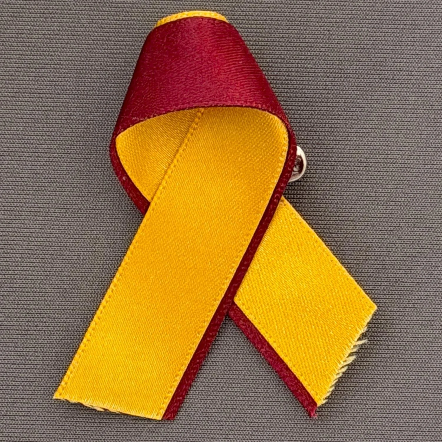 Reference Number: BCFIR024
Size: H 60 mm x W 50 mm
Pin Type: Safety Pin
Plating: N/A
Value: £5
Manufacturer: Bradford City Ribbons
Comments: Amber and Claret fabric ribbon produced by Georgia Thornton to raise money for PSBRU
