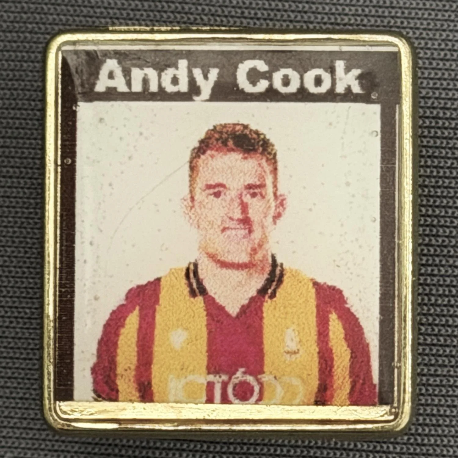 Reference Number: BCUN040
Size: H 24.2 mm x W 22.4 mm
Pin Type: Metal Clutch
Plating: Gold
Value: £4
Manufacturer: Guy, Manningham Lane
Comments: Andy Cook, Plastic Dome 2025