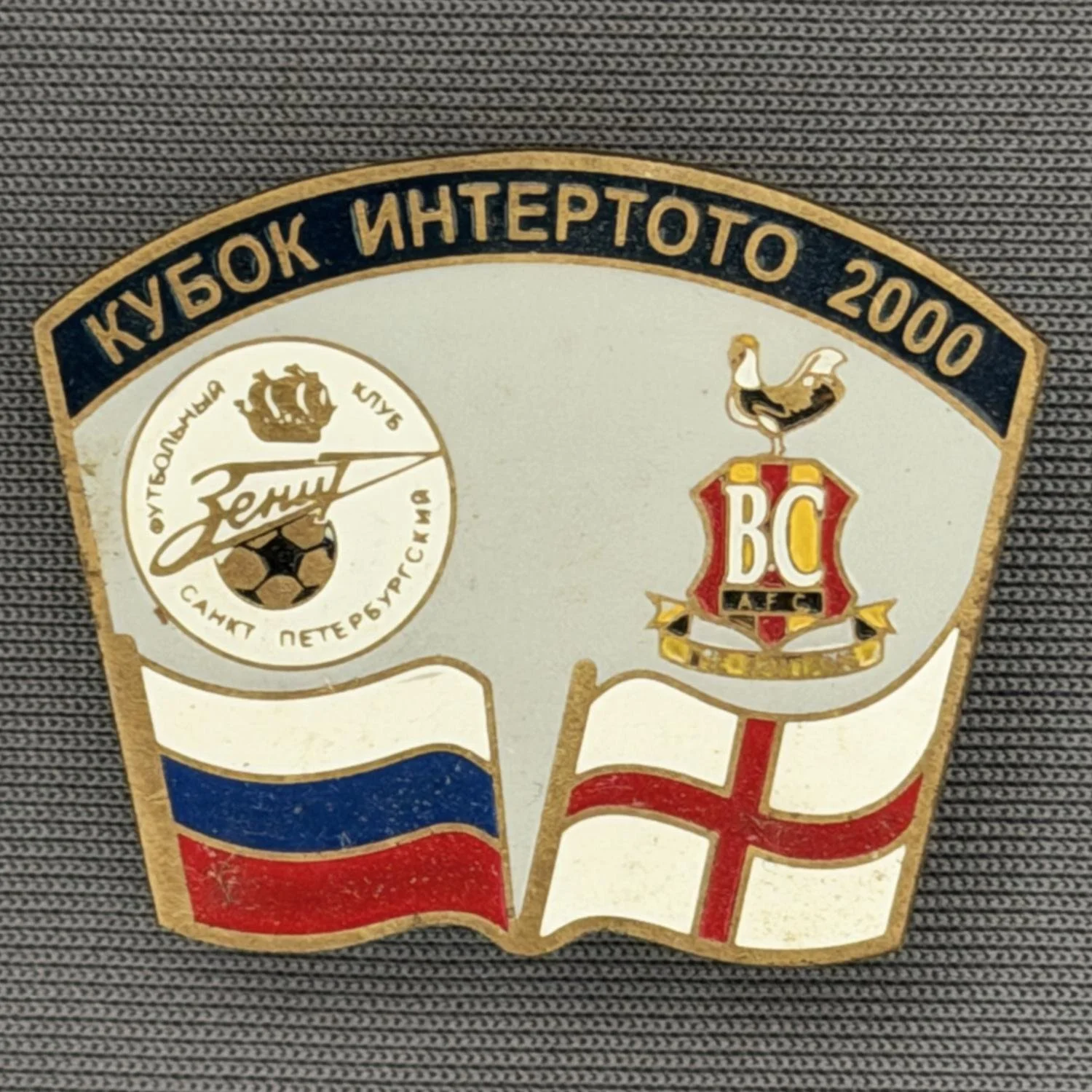 Reference Number: BCRUS031
Size: H 26 mm x W 32.3 mm
Pin Type: Metal Clutch
Plating: Antique Gold
Value: £12
Manufacturer: Unknown
Comments: Zenit St. Petersburg Inter Toto Cup, Dark Blue Top, Grey Background