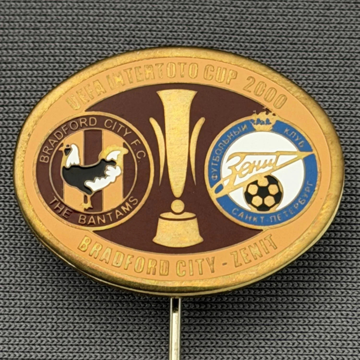 Reference Number: BCRUS044
Size: H 19.1 mm x W 24.9 mm
Pin Type: Metal Stick Pin
Plating: Gold
Value: £12
Manufacturer: Unknown
Comments: Inter Toto Cup, Bradford City v Zenit, Claret & Amber Version