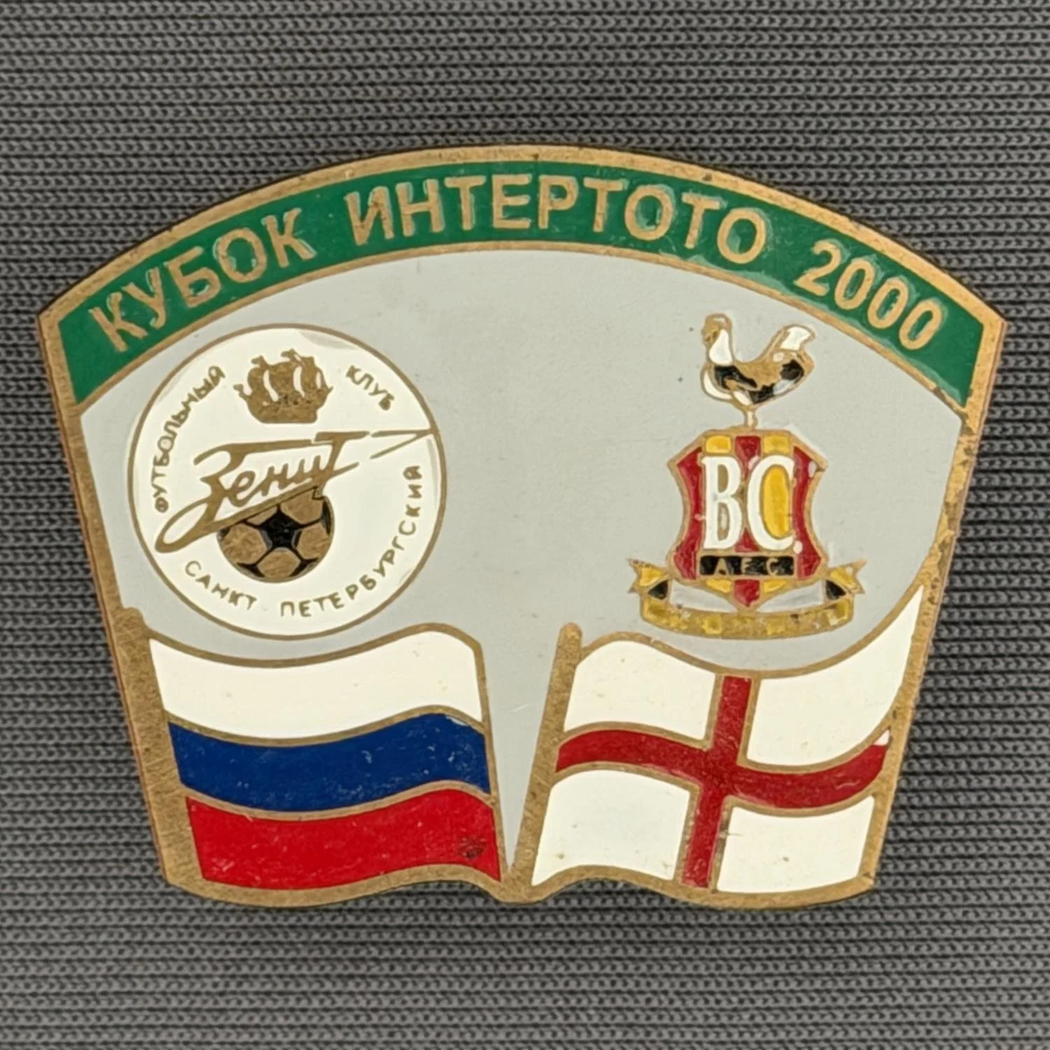 Reference Number: BCRUS033
Size: H 26 mm x W 32.3 mm
Pin Type: Metal Clutch
Plating: Antique Gold
Value: £12
Manufacturer: Unknown
Comments: Zenit St. Petersburg Inter Toto Cup, Green Top, Grey Background