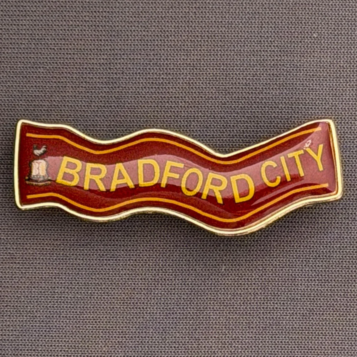 Reference Number: BCSCA011
Size: H 13.8 mm x W 39.7 mm
Pin Type: Brooch Pin
Plating: Gold
Value: £4
Manufacturer: Unknown
Comments: Claret & Amber Bradford City Scarf with City Logo