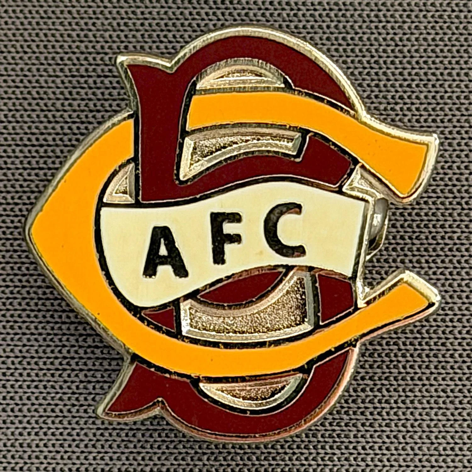 Reference Number: BCC&L071
Size: H 20.6 mm x 20.8  mm
Pin Type: Brooch Pin
Plating: Silver
Value: £6
Manufacturer: Unknown
Comments: BCFC Ayrton Scroll Claret & Amber Smaller Version