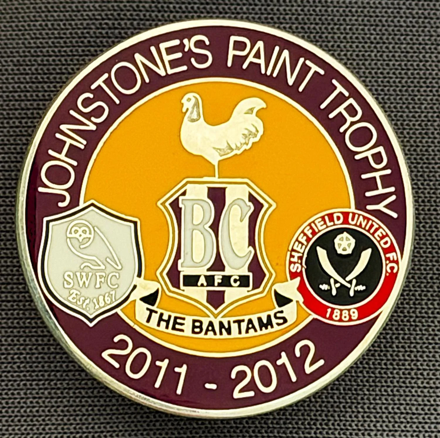 Reference Number: BCOFIX070
Size: D 25.8 mm
Pin Type: Brooch Pin
Plating: Chrome
Value: £5
Manufacturer: Unknown
Comments: Johnstones Paint Trophy 2011/12 Bradford City, Sheff United, Sheffield  Wednesday, Claret & Amber Version