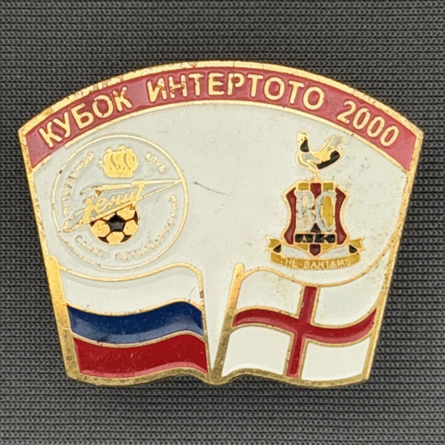 Reference Number: BCRUS026
Size: H 26 mm x W 32.3 mm
Pin Type: Metal Clutch
Plating: Antique Gold
Value: £12
Manufacturer: Unknown
Comments: Zenit St. Petersburg Inter Toto Cup, Pink Top, White Background